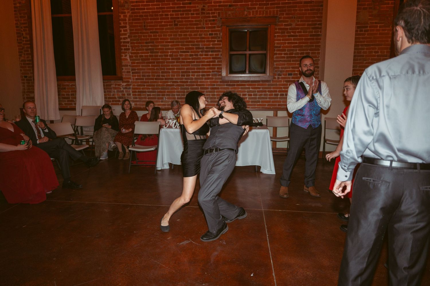 Couples dancing together at wedding reception in rustic brick venue.