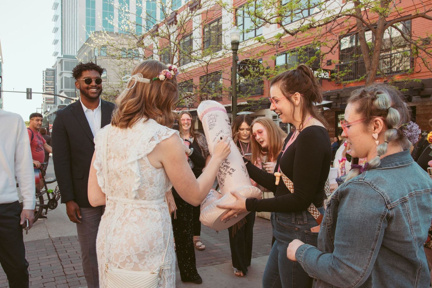 Wedding guests mingling and celebrating at an outdoor urban venue with tall buildings in background.