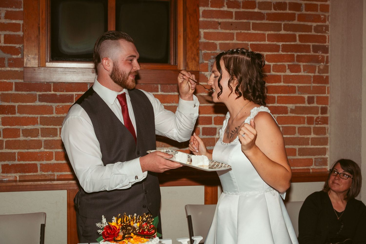 Wedding party celebrating with cake and dancing in an industrial-style venue.