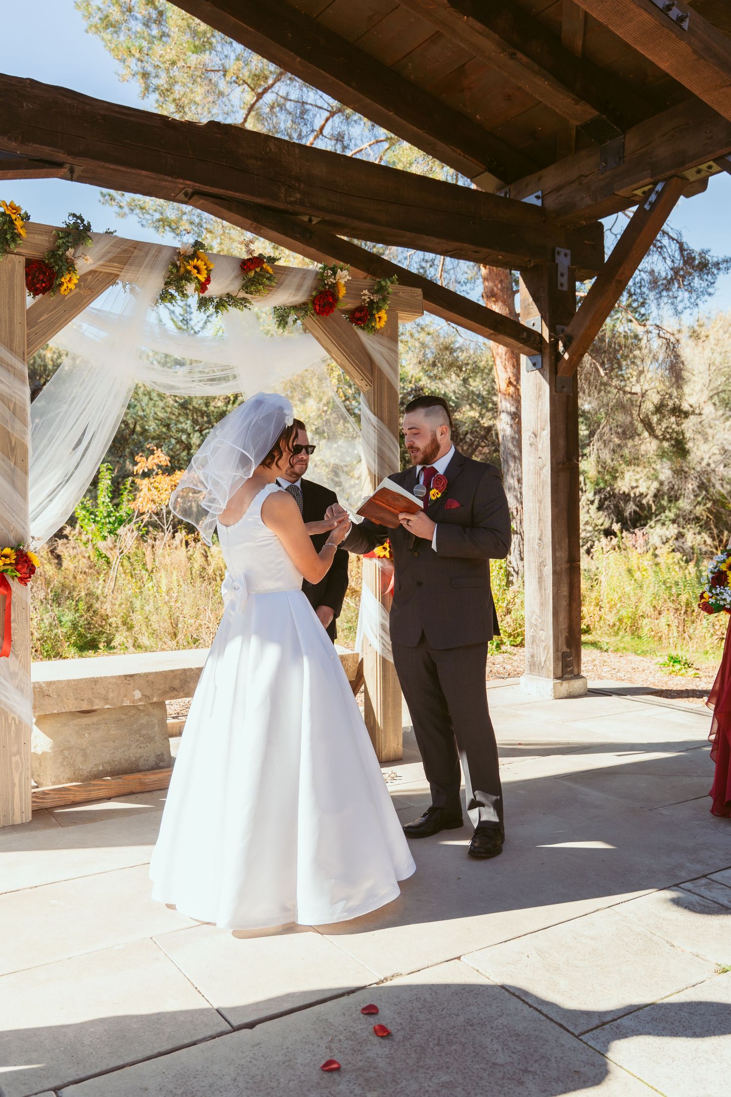 Wedding ceremony moments captured under a wooden pergola with white fabric decorations.