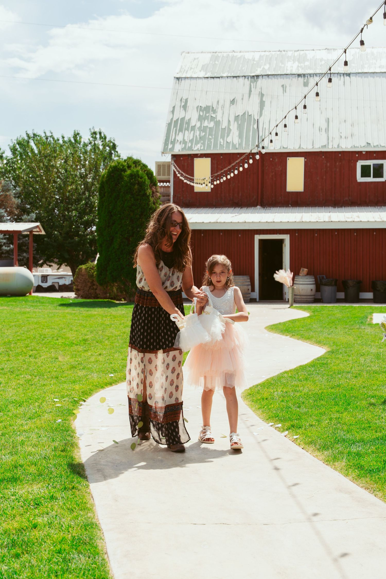 A series of five photos showing people walking down a concrete path next to a red barn on a sunny day.