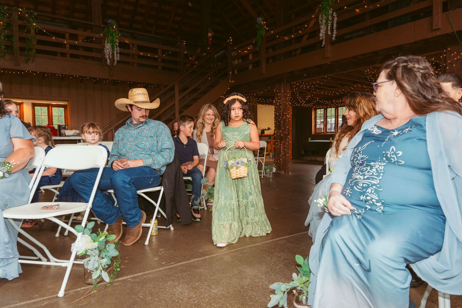 Wedding celebration inside a rustic barn with guests mingling and dancing.