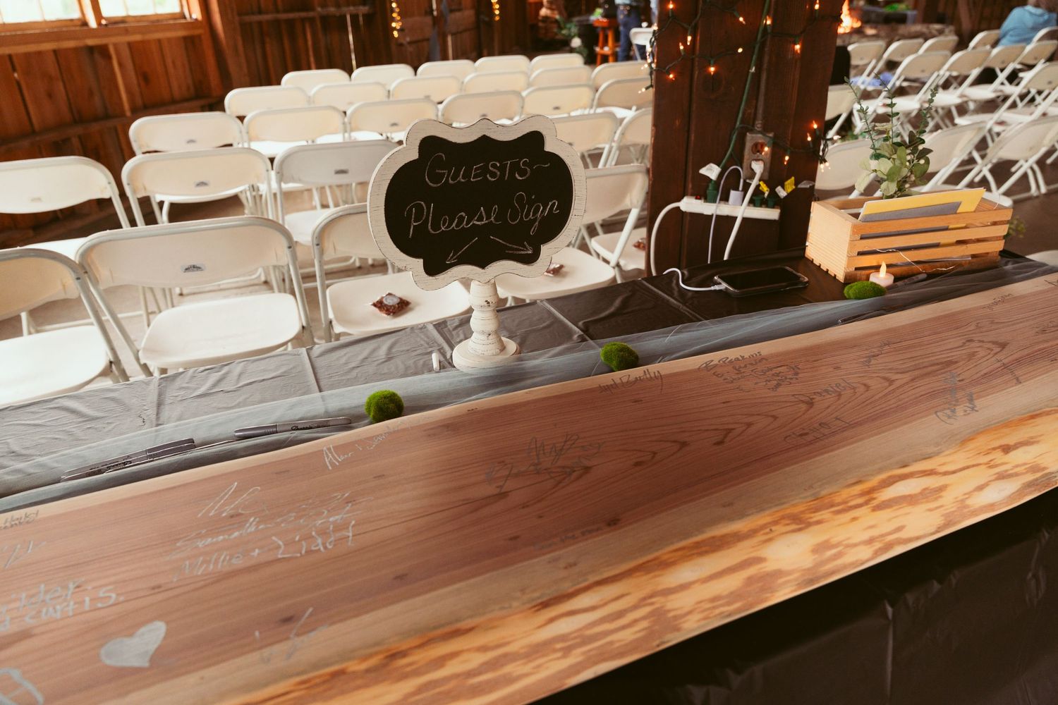 Rustic wooden bar setup with glassware and decorative signs for a wedding reception.