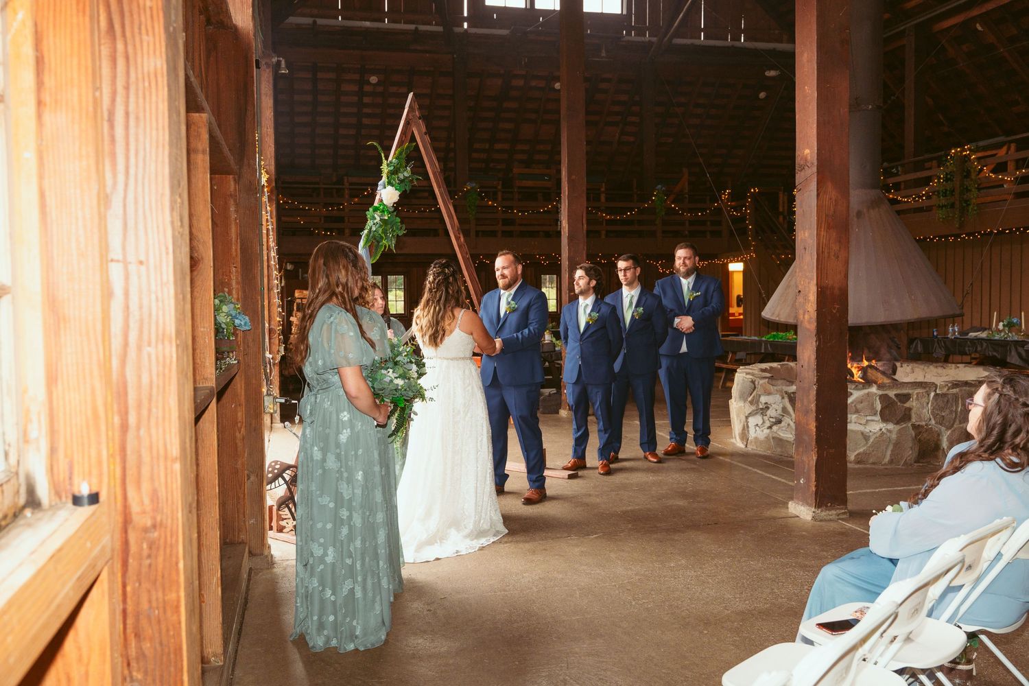 Wedding ceremony setup in rustic barn with rows of white chairs and natural lighting.