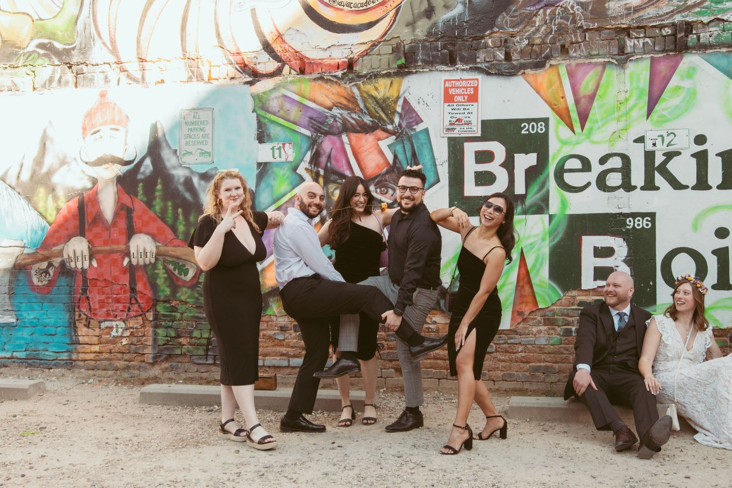 Wedding party poses playfully in front of a colorful Breaking Bad themed graffiti wall.