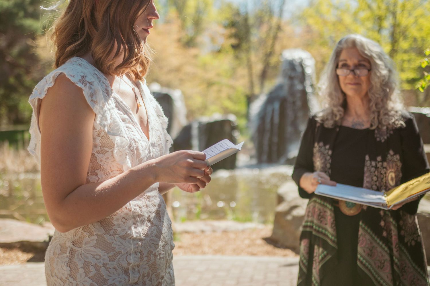 A group of people in formal attire gather outdoors for a special event on a sunny autumn day.