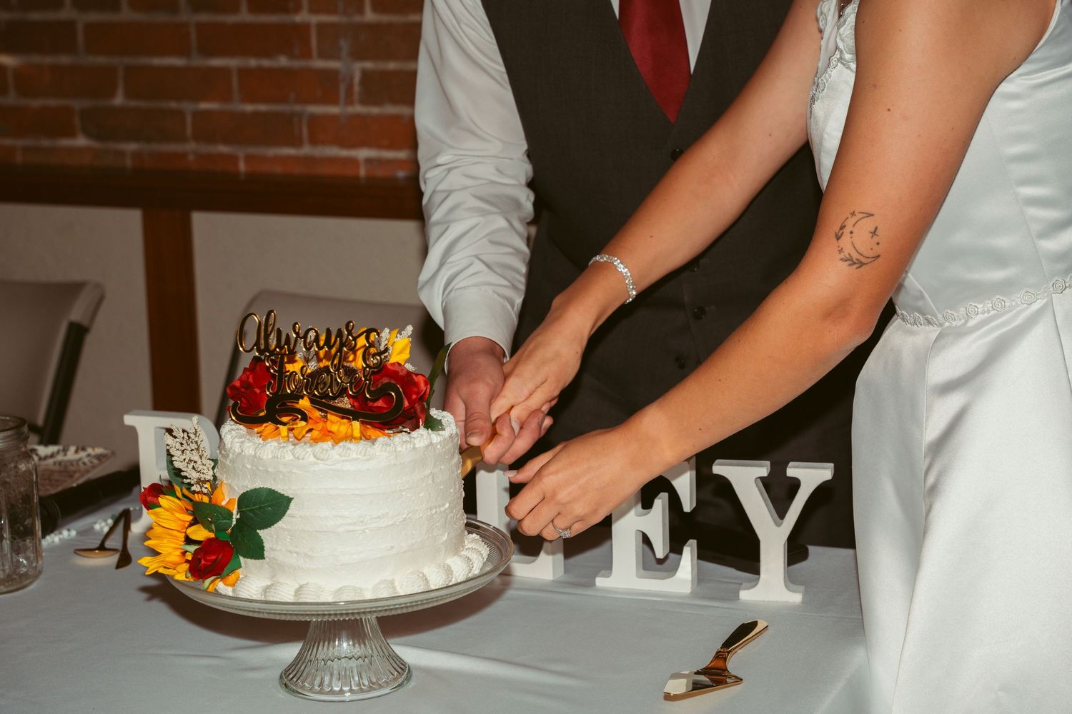 Close-up of wedding cake being cut with floral decorations visible.