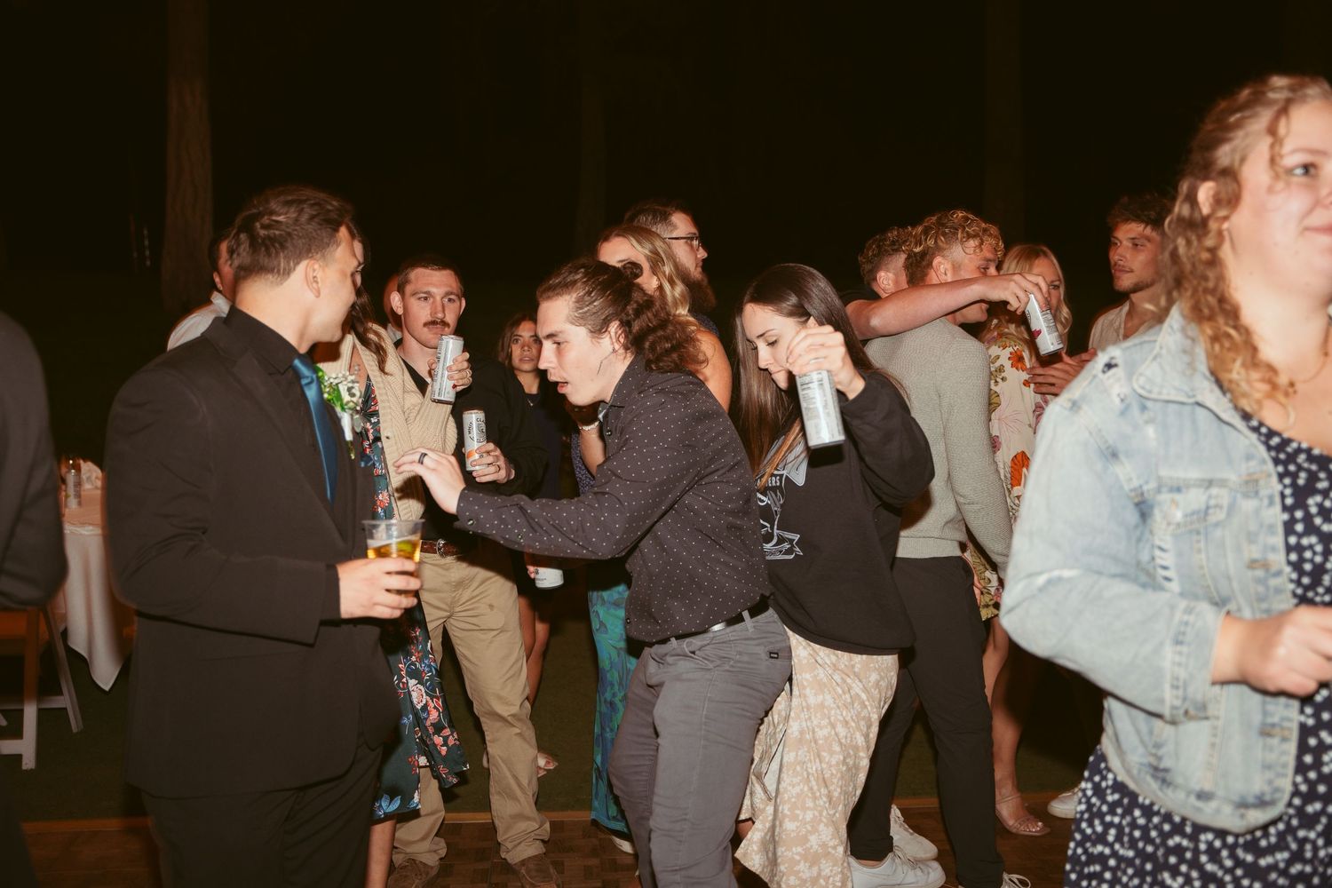 Wedding party dancing and celebrating at nighttime outdoor reception.
