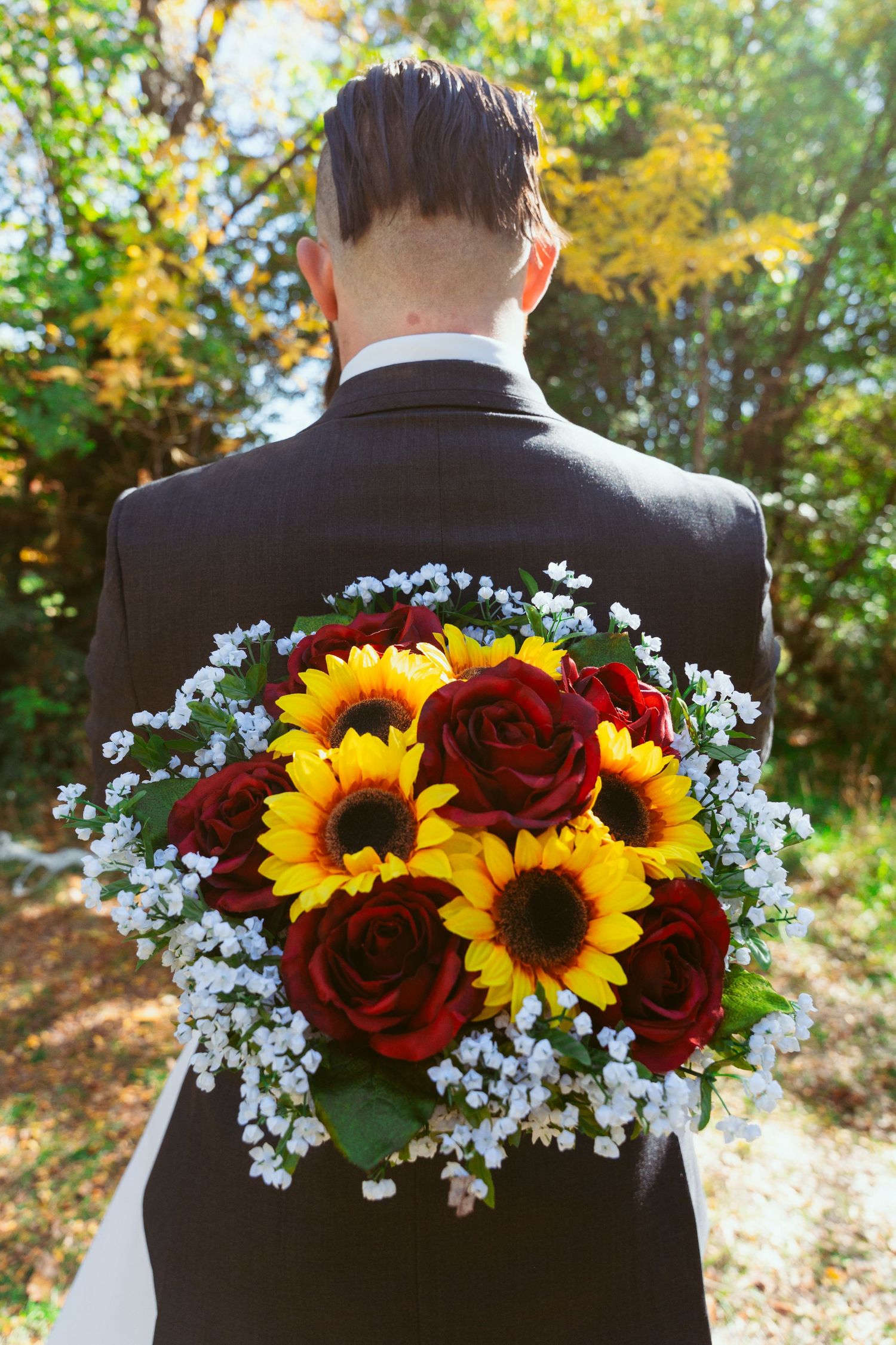 Floral arrangement with sunflowers, red roses, and baby's breath decorating the back of a dark suit.
