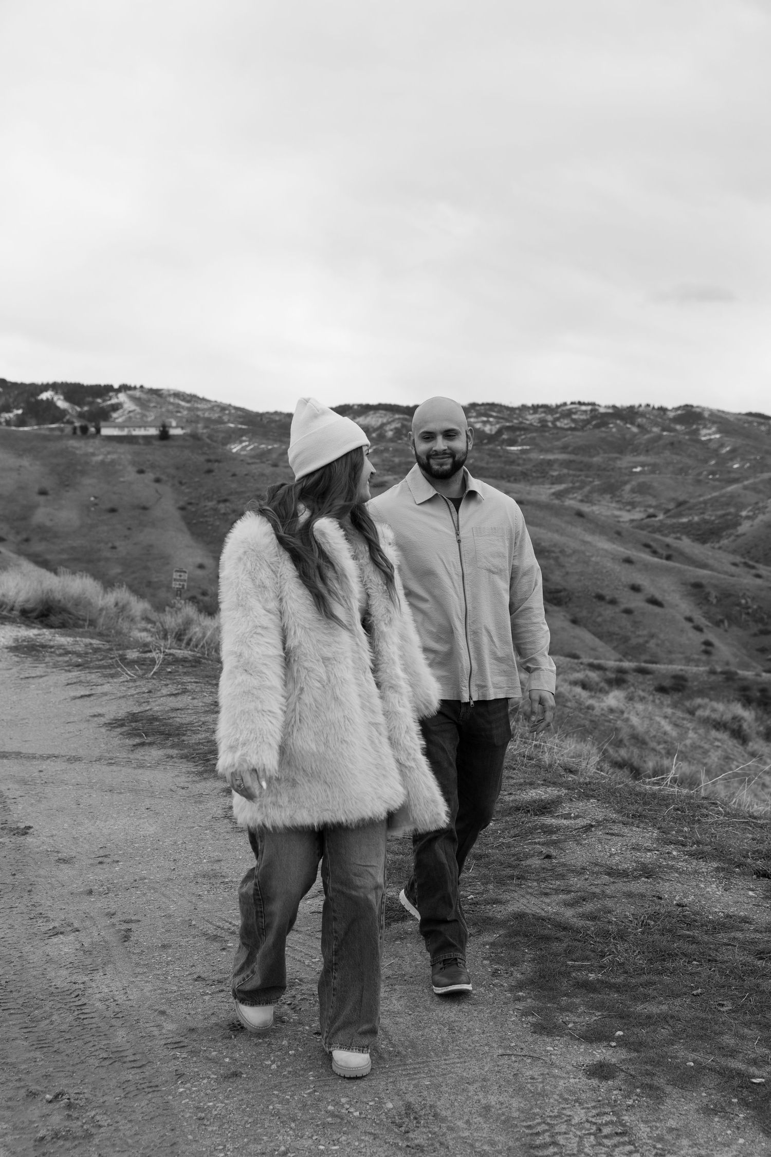 Two people walking together on a desert trail wearing light colored clothing.