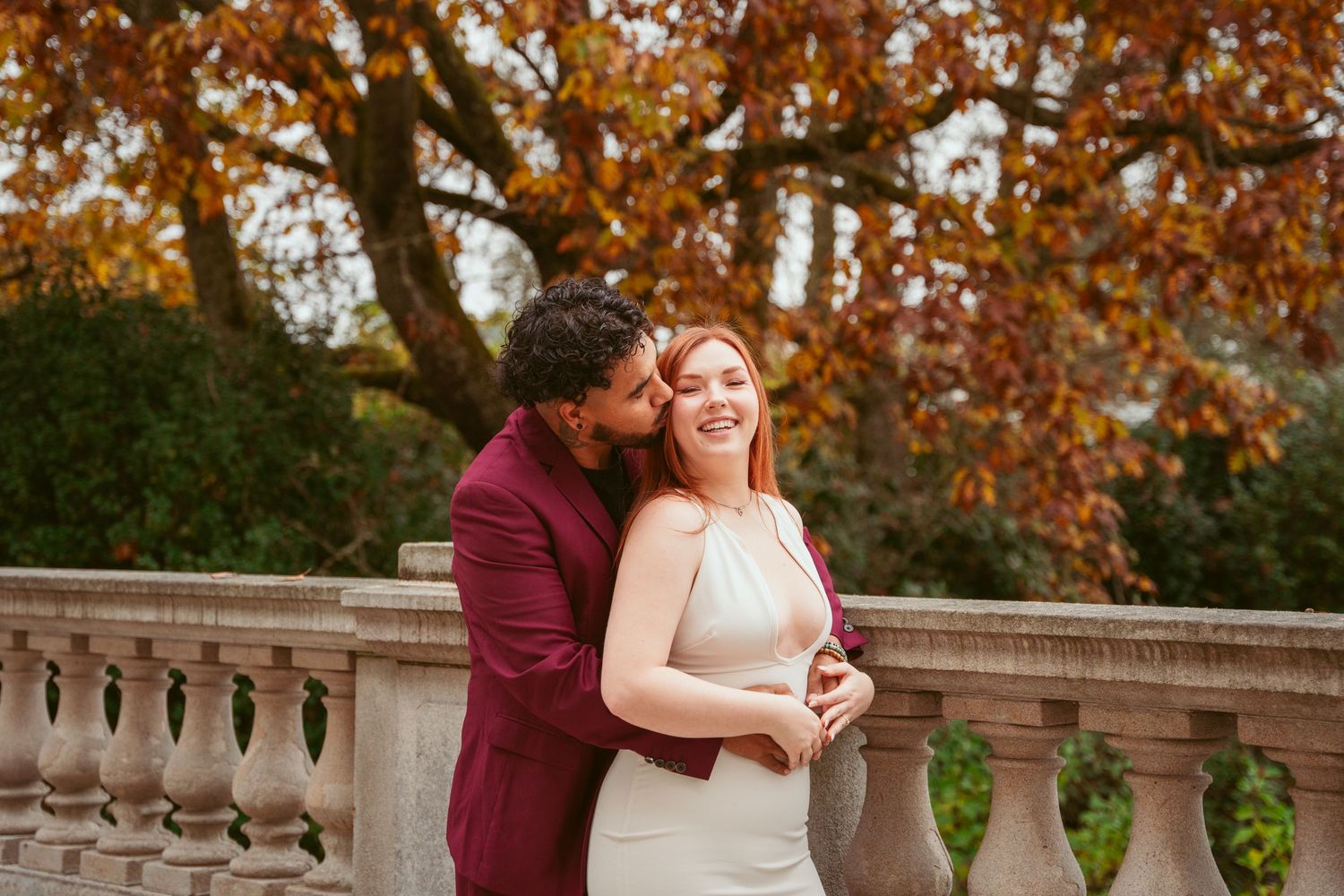 Couple sharing a romantic moment outdoors during autumn with orange leaves in the background.