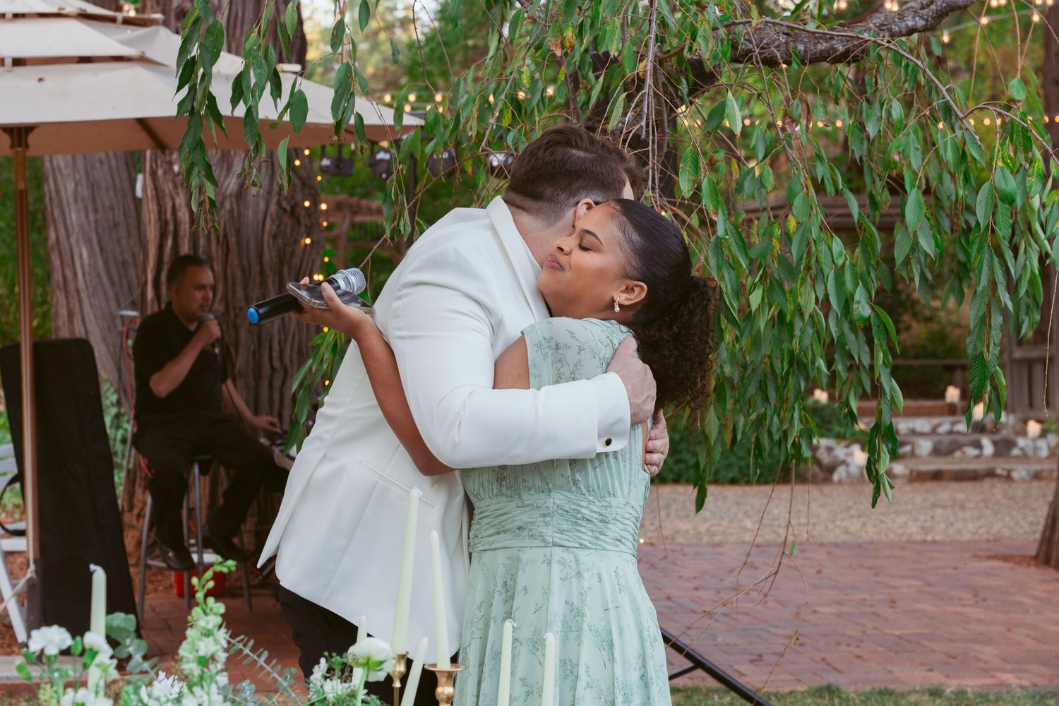 Couples dancing together under green foliage at an outdoor wedding.