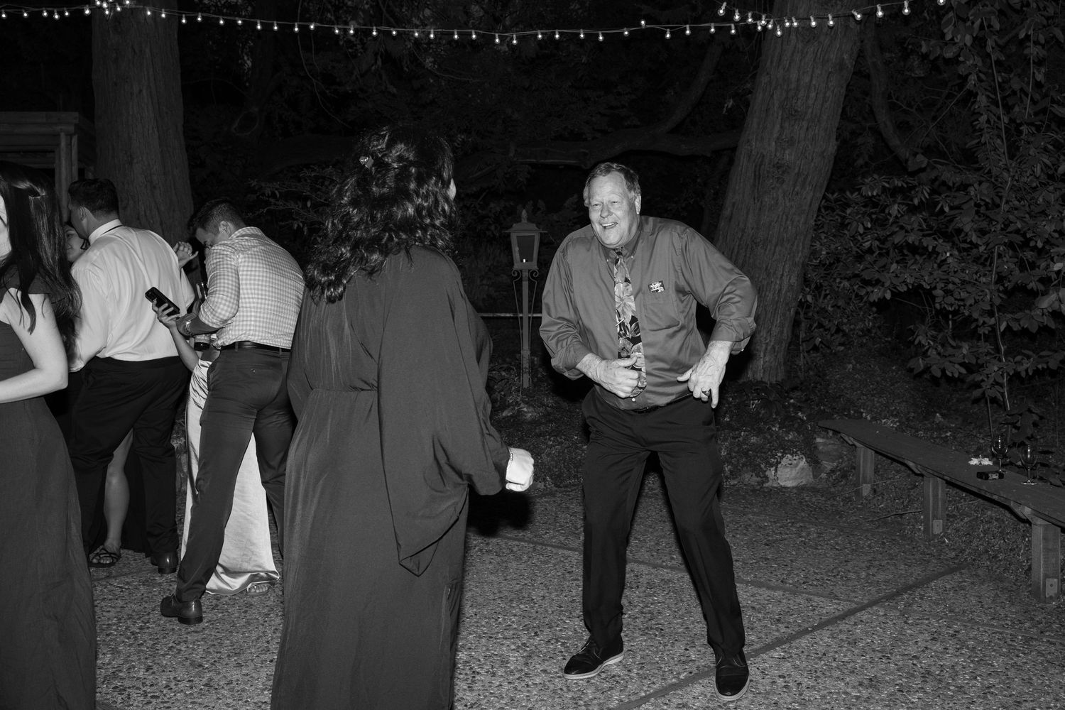 Black and white photo of guests dancing at a nighttime wedding celebration.