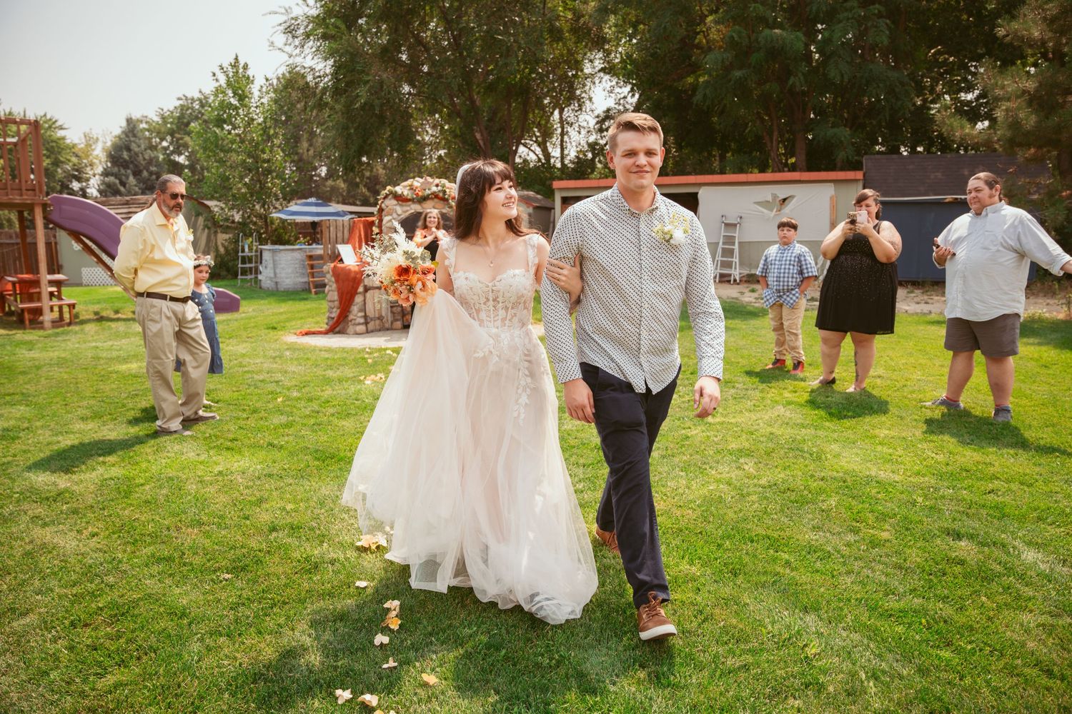 Wedding celebration on grassy lawn with guests gathered outdoors.