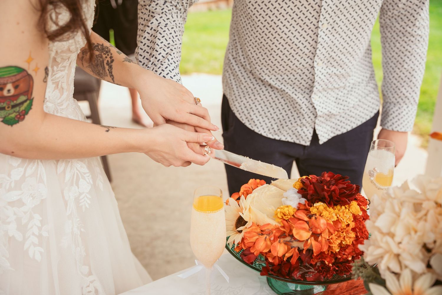 Close-up of hands holding vibrant orange and red floral bouquets at a wedding celebration.
