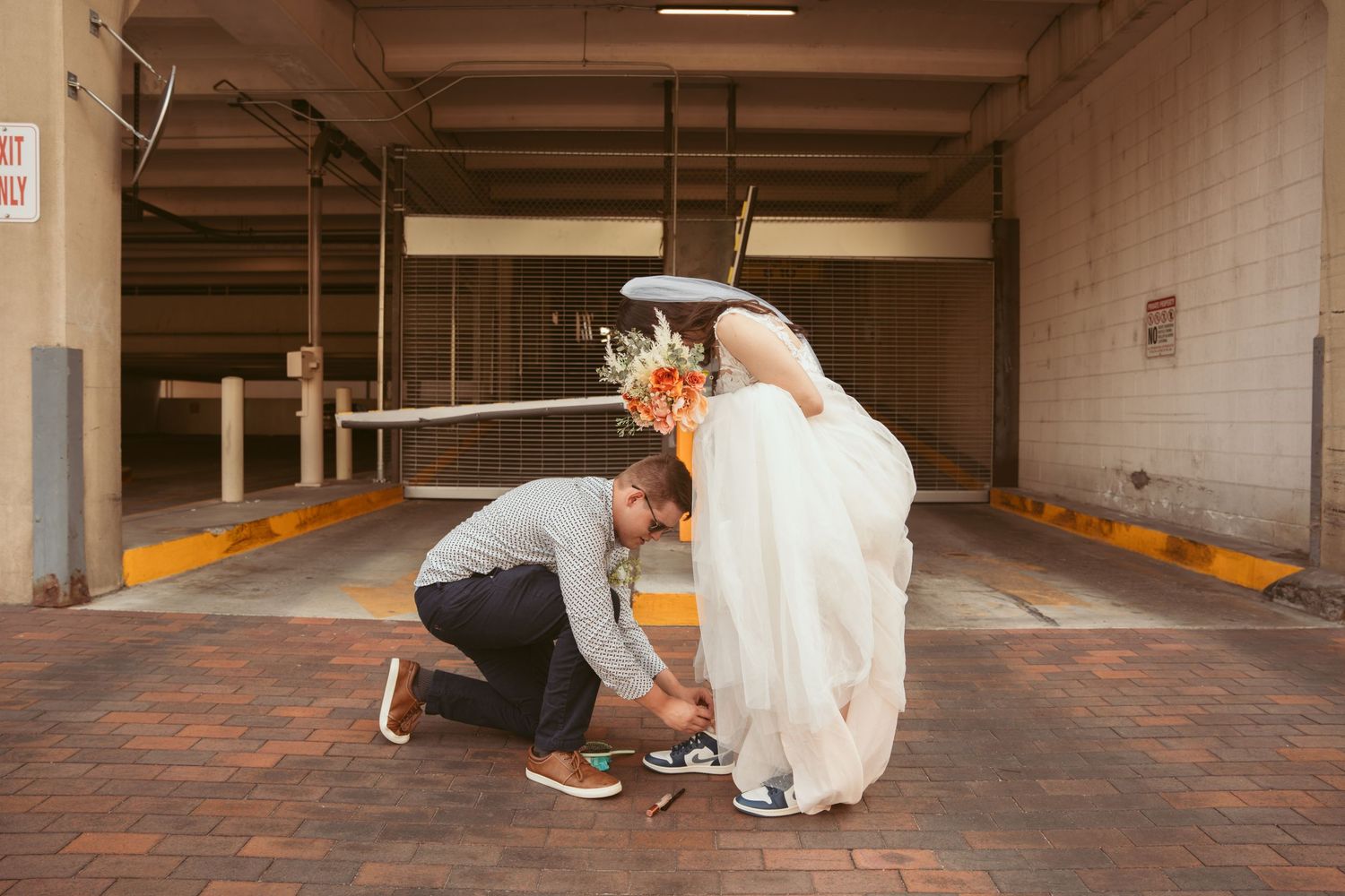 People in formal attire walking through a concrete parking structure.