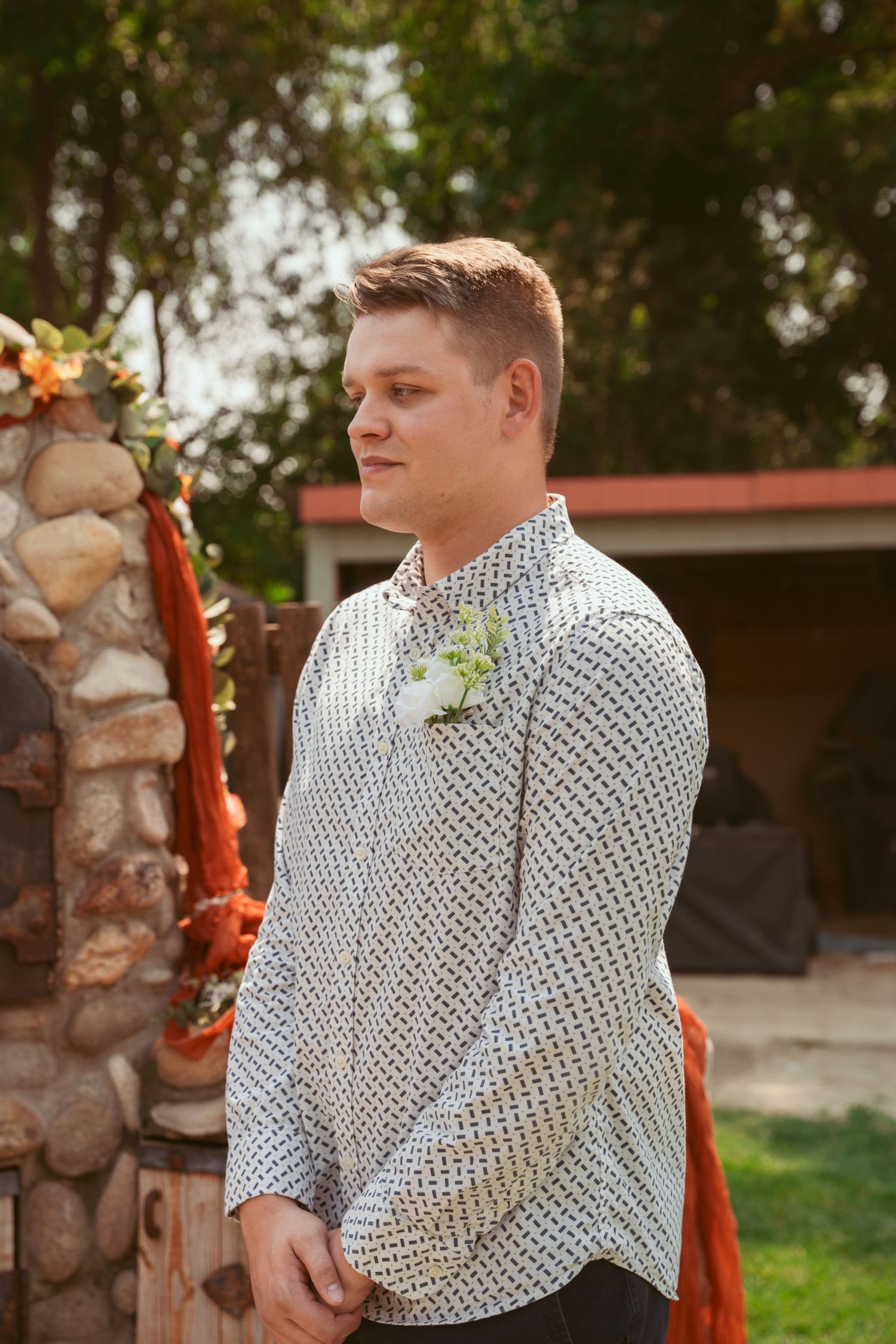 Person in a polka dot shirt stands near stone pillars during an outdoor event.