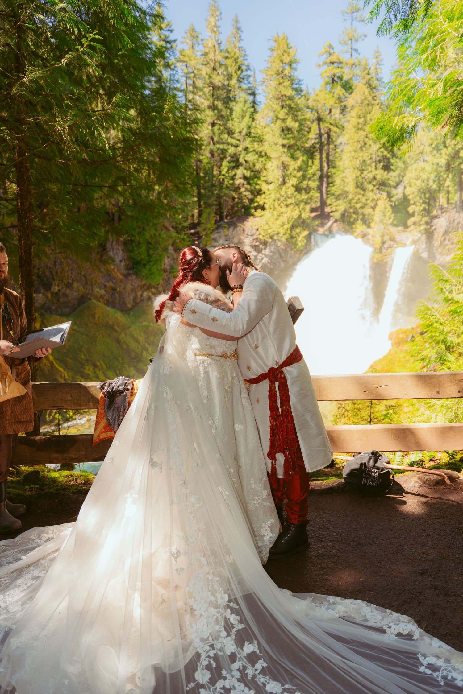 A couple shares their first dance as newlyweds in front of a cascading waterfall.