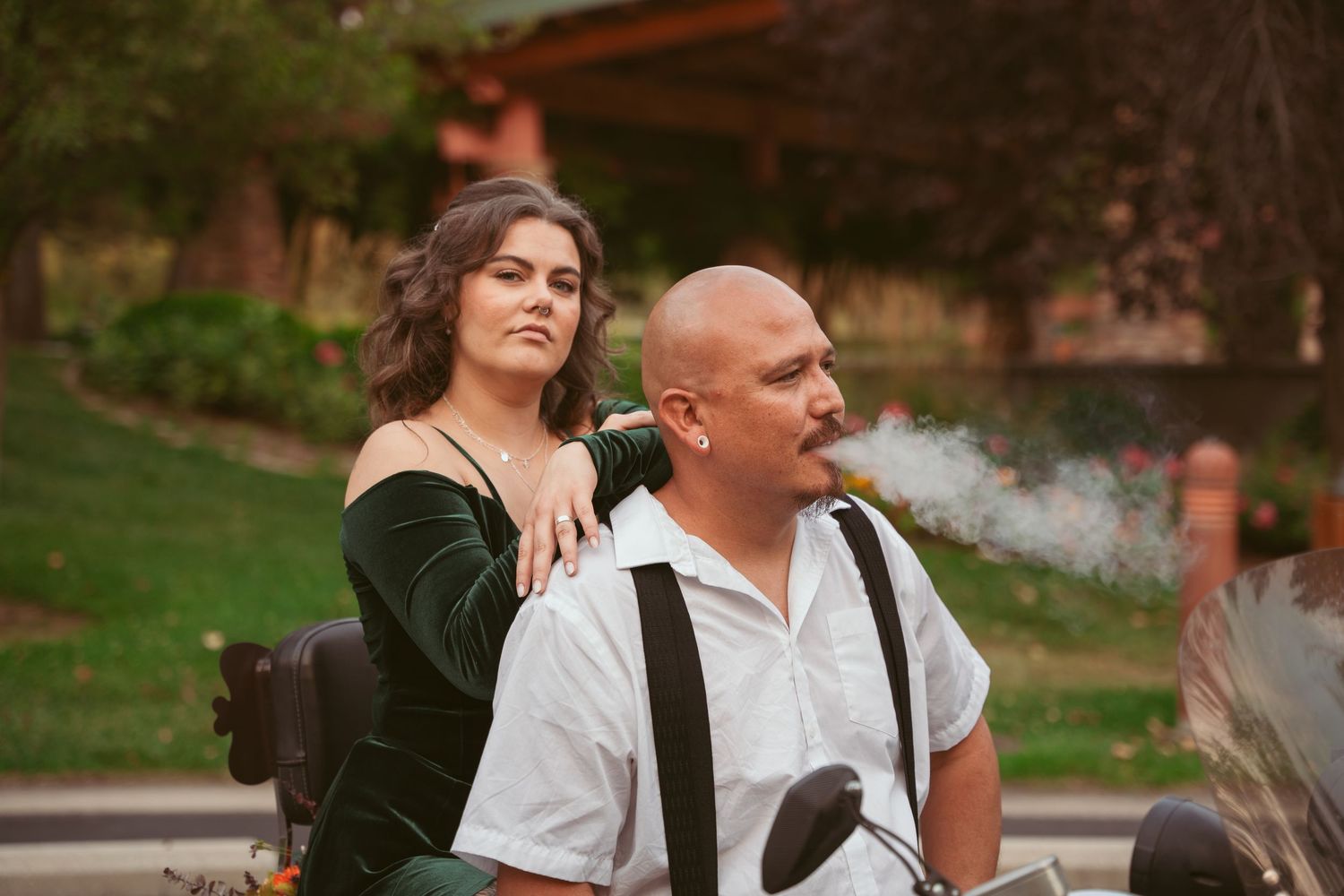 Outdoor couples photoshoot featuring a motorcycle and natural garden backdrop.