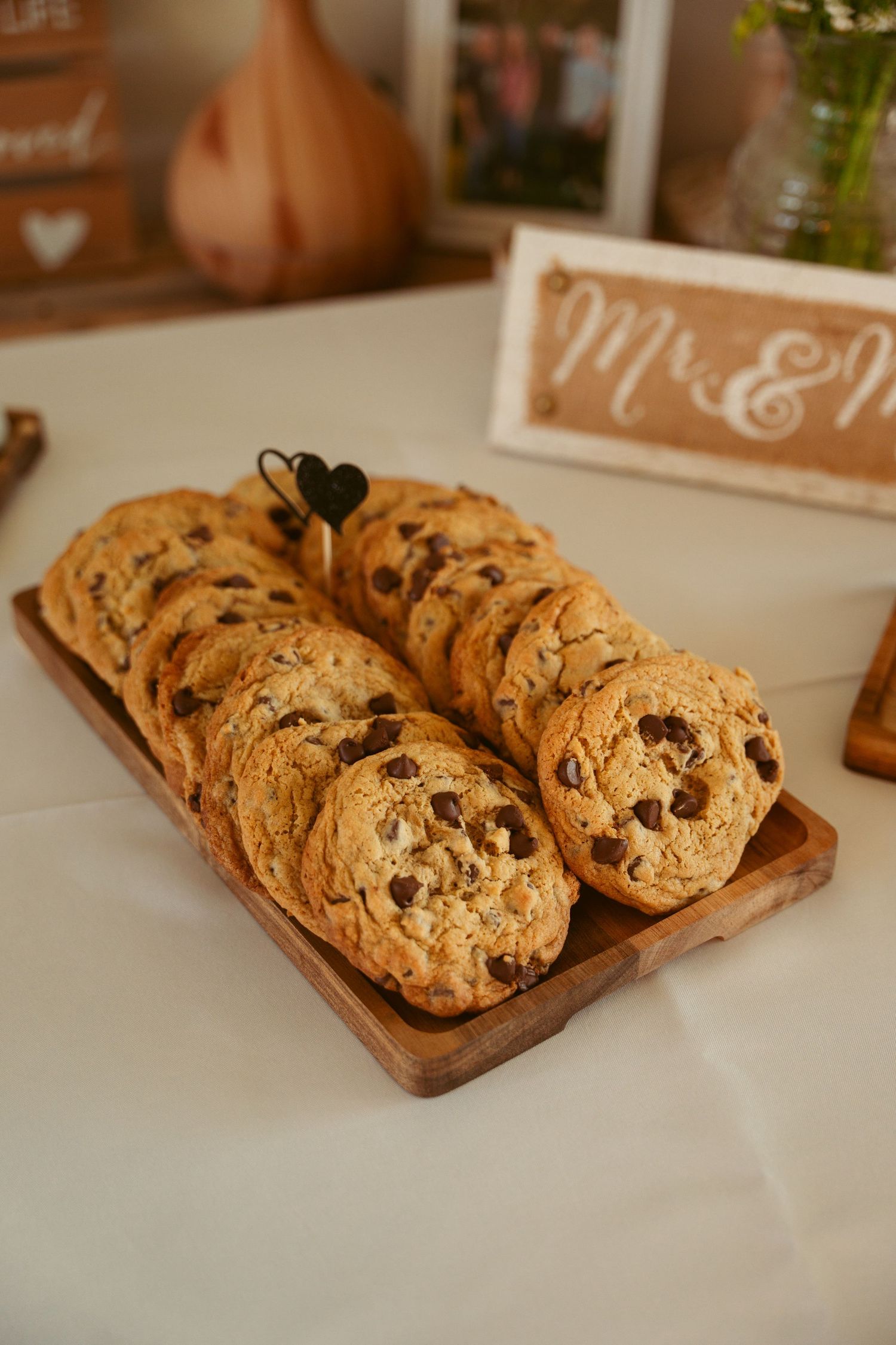 Fresh chocolate chip cookies displayed on wooden serving boards at a wedding reception.
