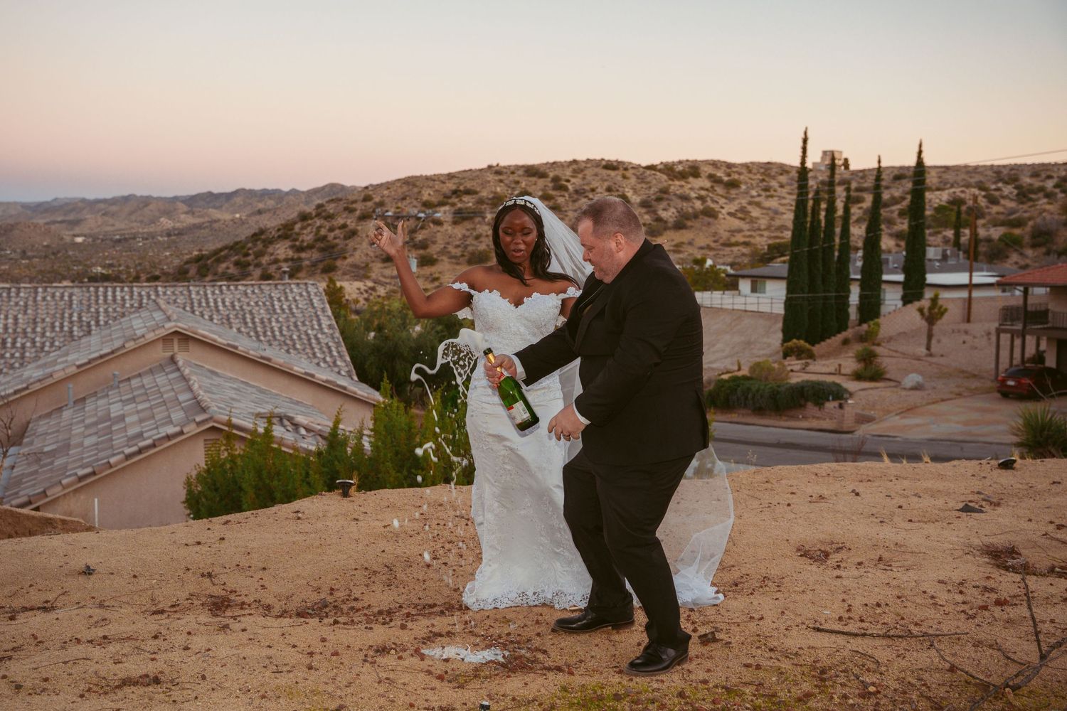 A joyful wedding dance moment against a desert landscape at sunset.