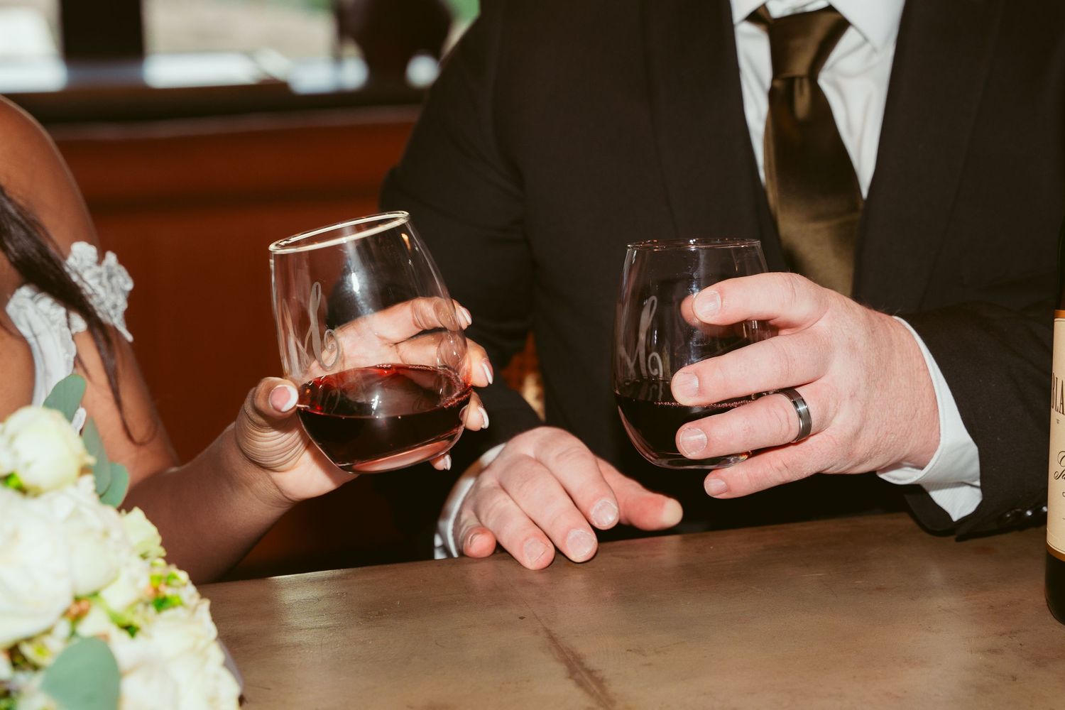 Close-up of hands and wine glasses at a wedding reception table.