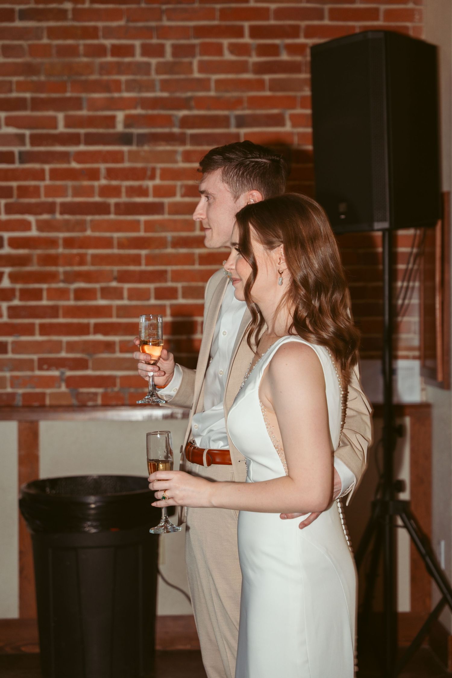 Wedding guests enjoying drinks and conversation in a rustic brick venue.