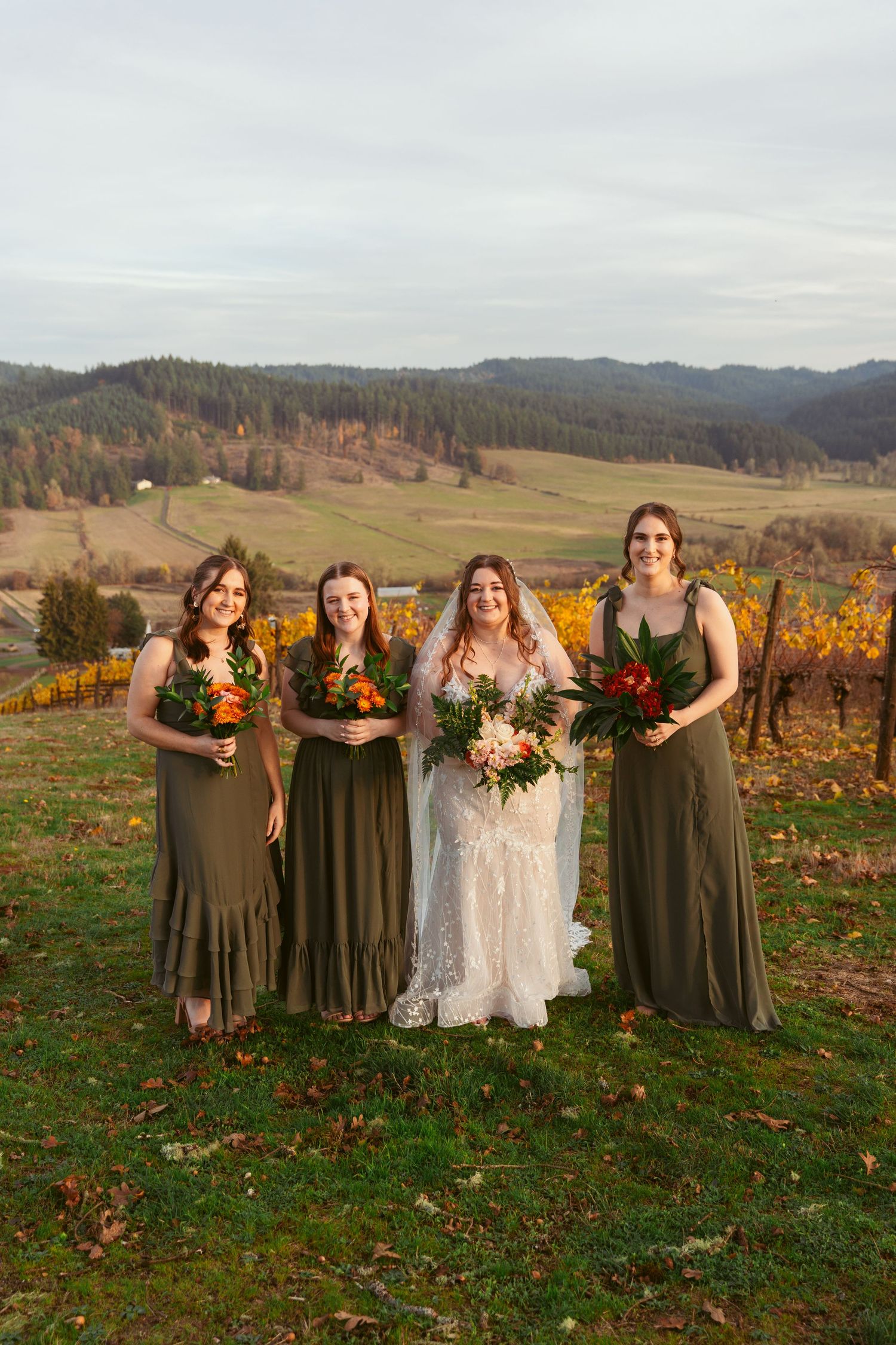 Bridal party stands together on hillside with fall foliage and vineyards in background.