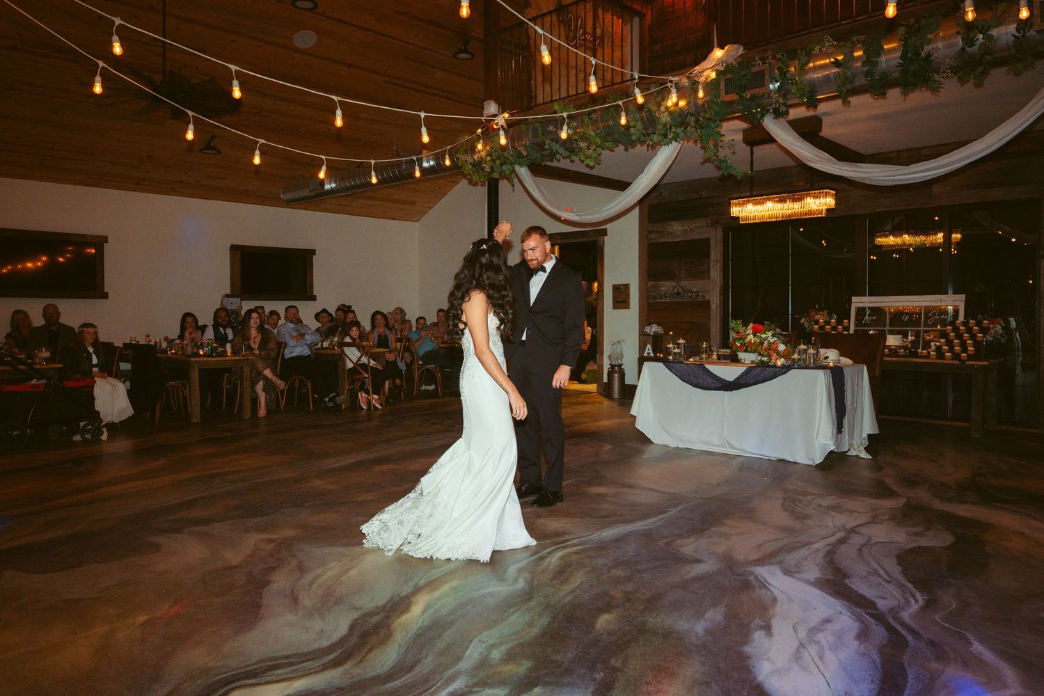 Wedding reception dance floor illuminated by overhead string lights in evening celebration.