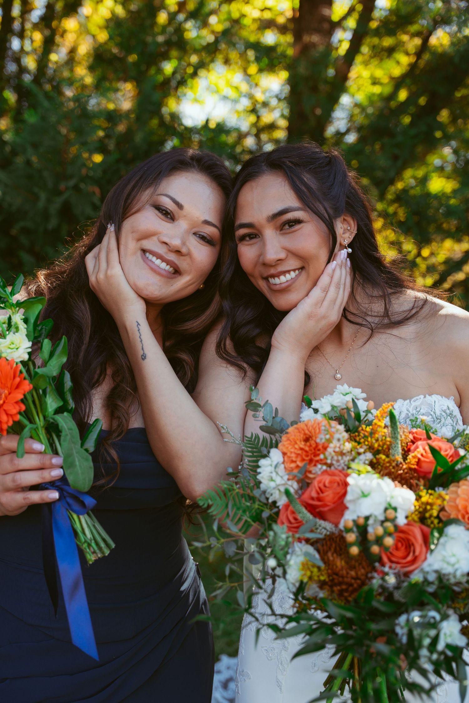 Joyful wedding moment captured with bright orange bouquets against sunlit forest background.
