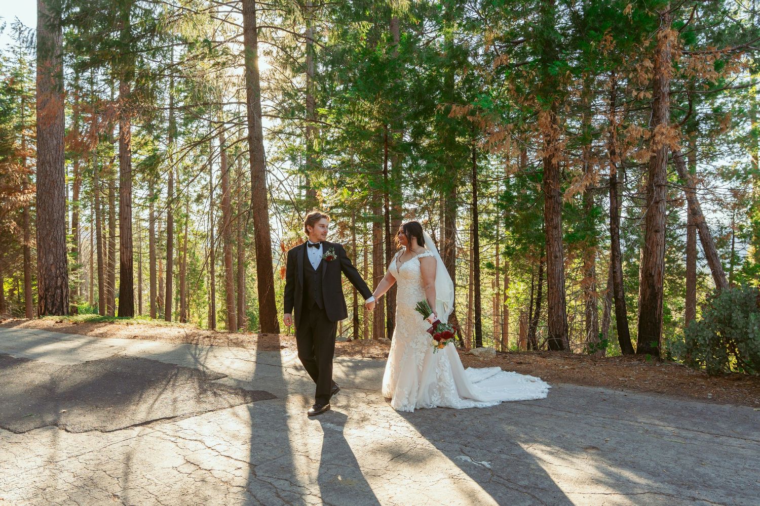 A romantic wedding photoshoot in a sunlit forest with tall pine trees creating a magical backdrop.