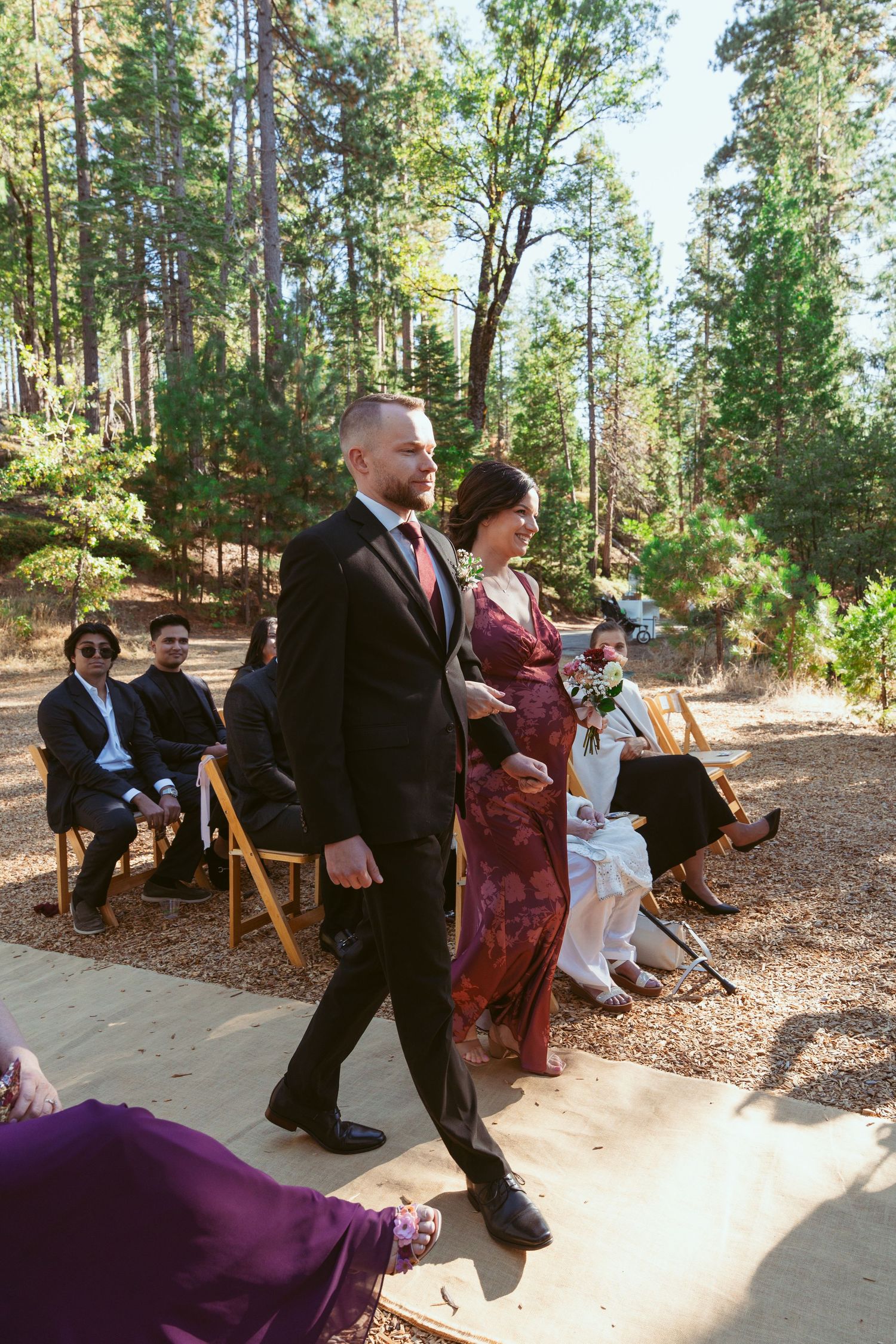 Wedding party members walking and interacting on stone pathway during outdoor celebration.
