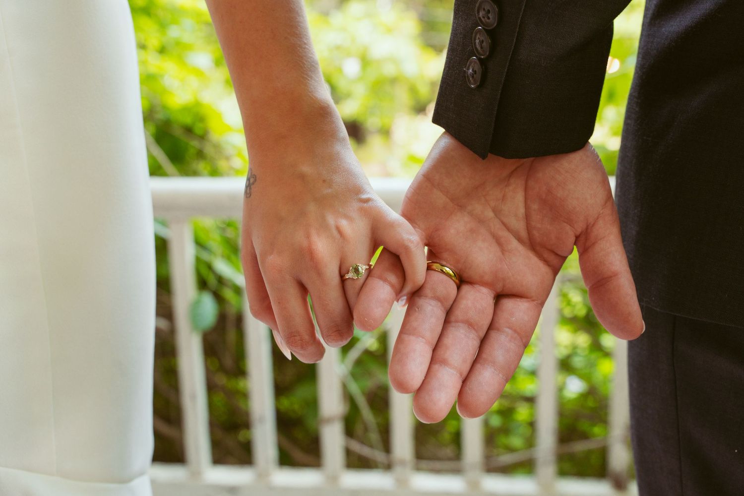 Close-up of hands during a wedding ceremony with white columns visible.