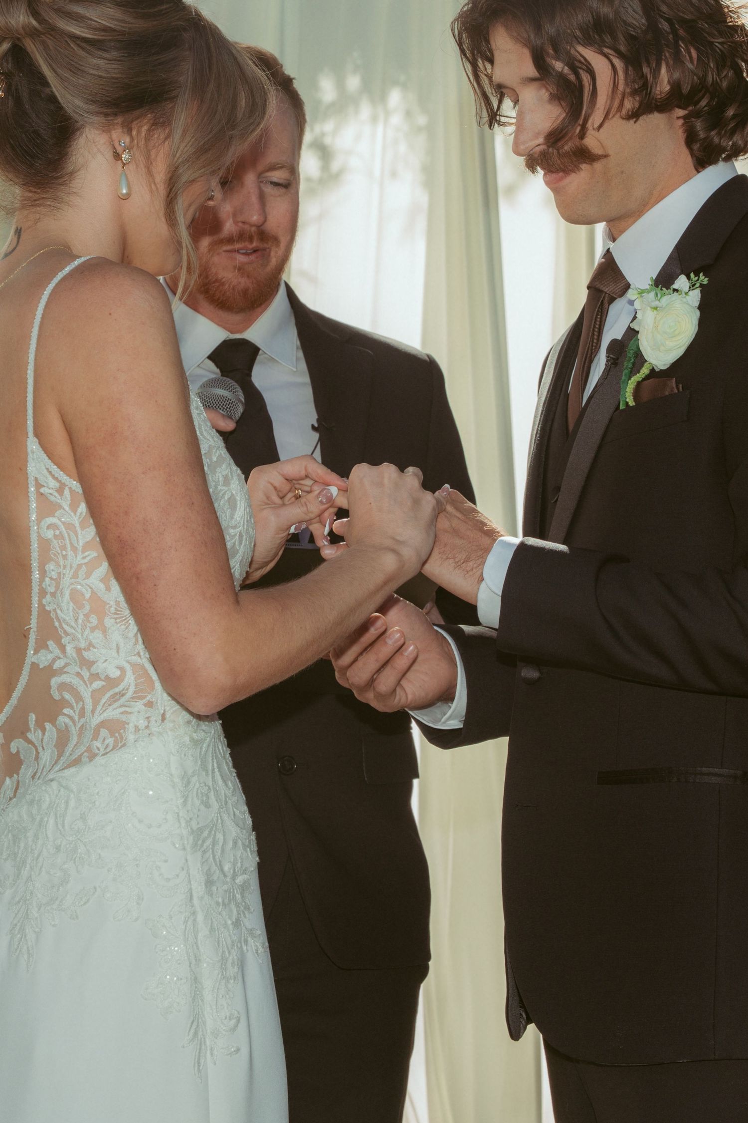 An intimate moment during a ring exchange at an outdoor forest wedding ceremony.