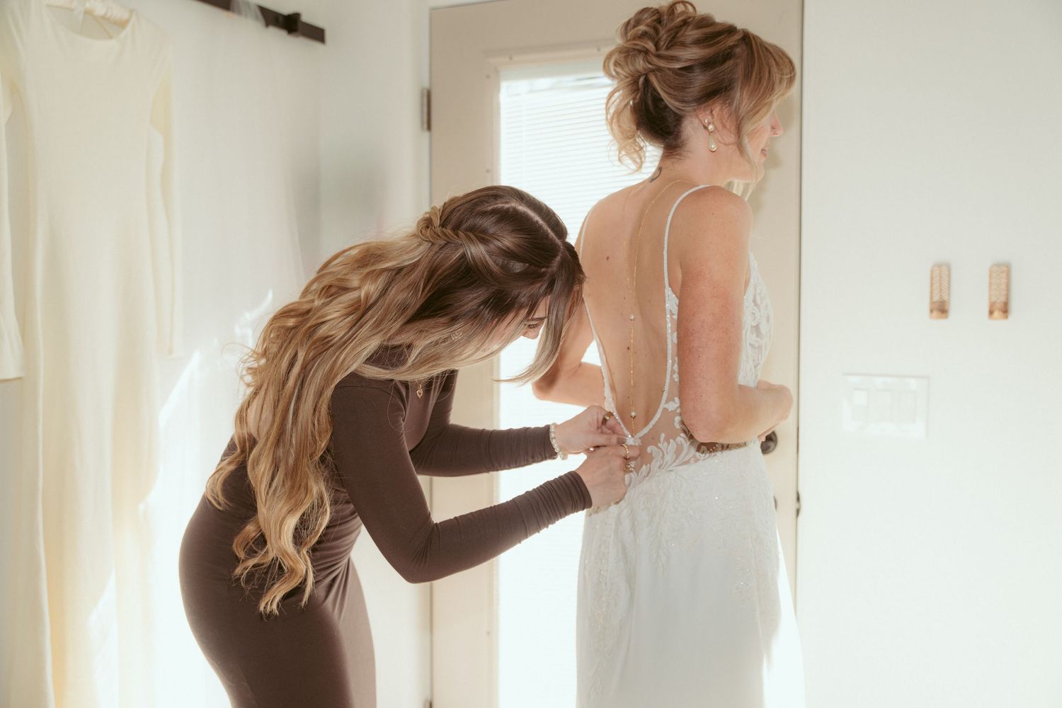 A series of photos showing the process of buttoning up a detailed wedding dress.