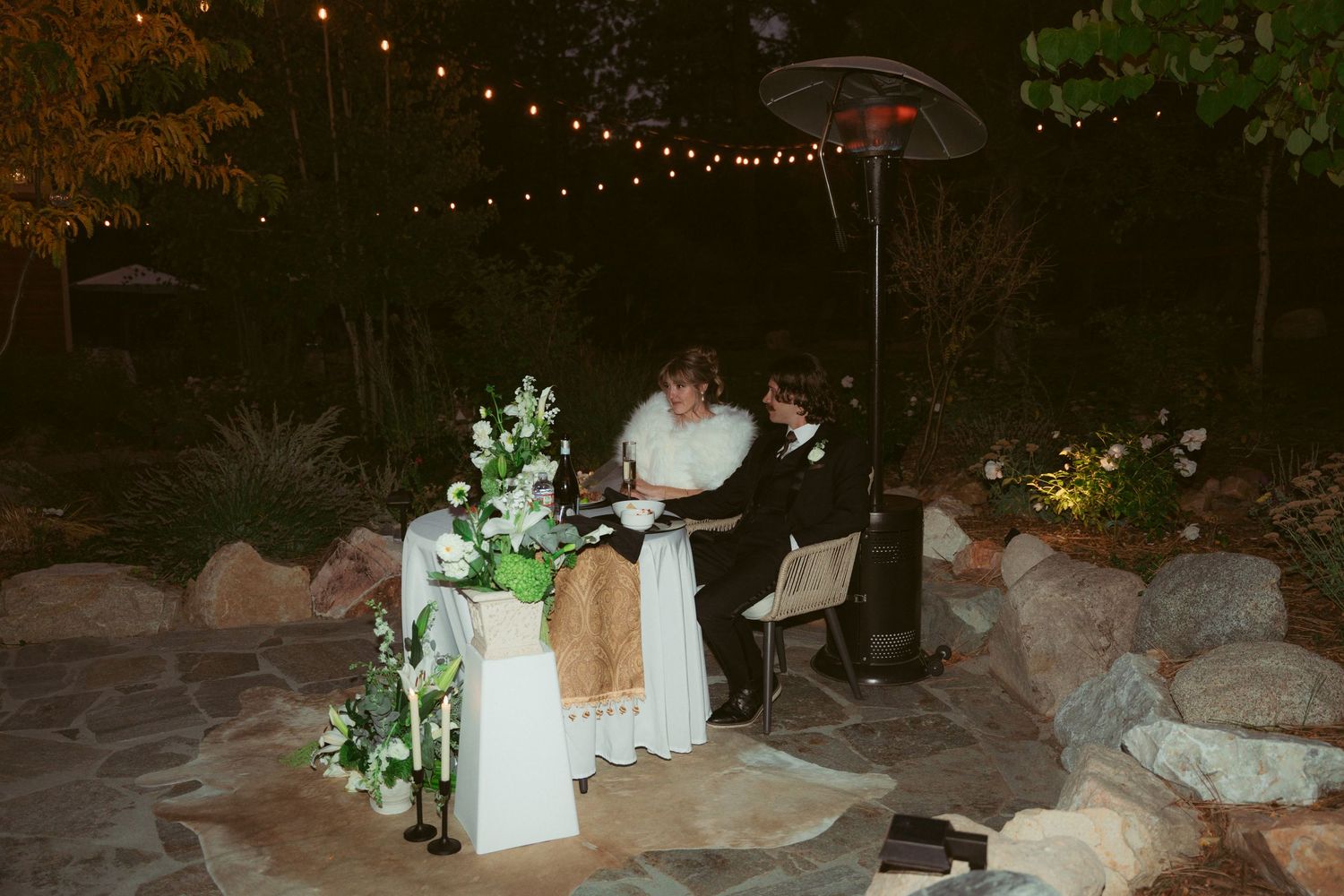 Nighttime outdoor celebration with twinkling string lights and elegant table settings.