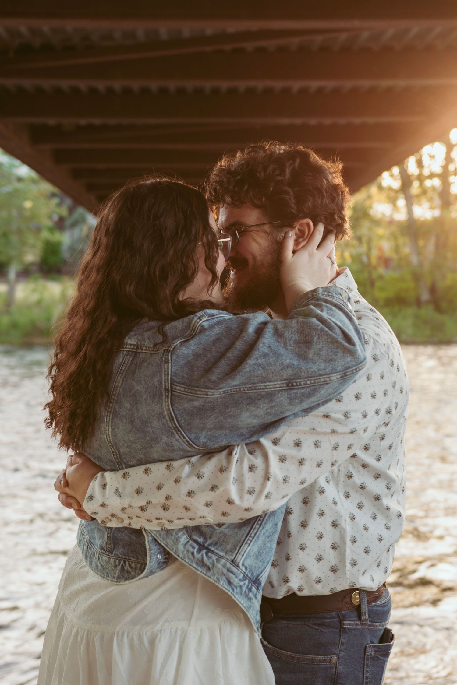 Romantic couple embracing in denim and polka dots during golden hour.