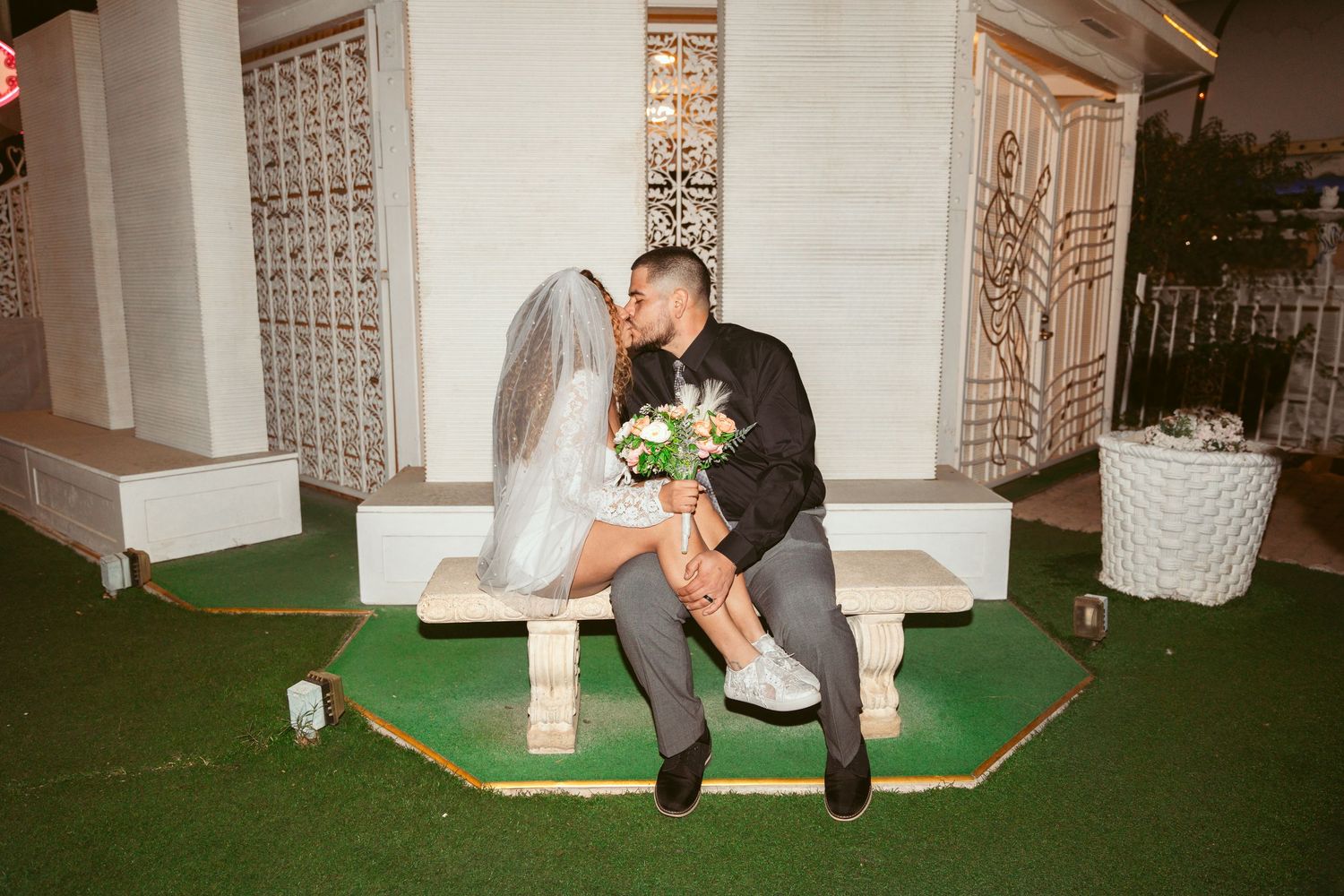 A couple shares a romantic moment in front of an ornate wedding chapel entrance.