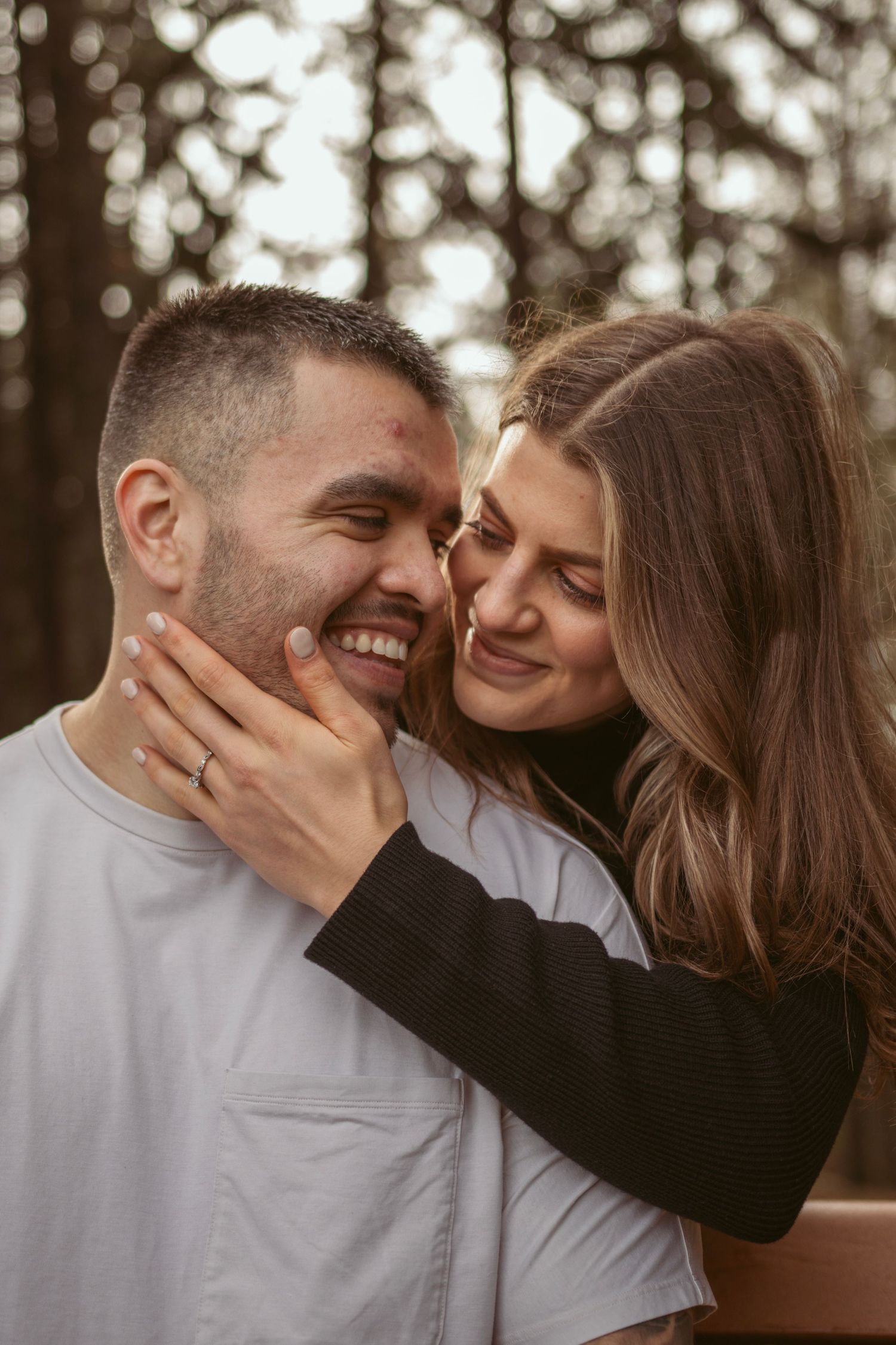 Playful couple laughing and touching faces in outdoor portrait session.