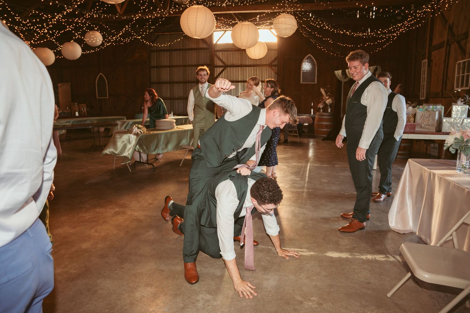 People dancing at a festive indoor celebration with string lights overhead.