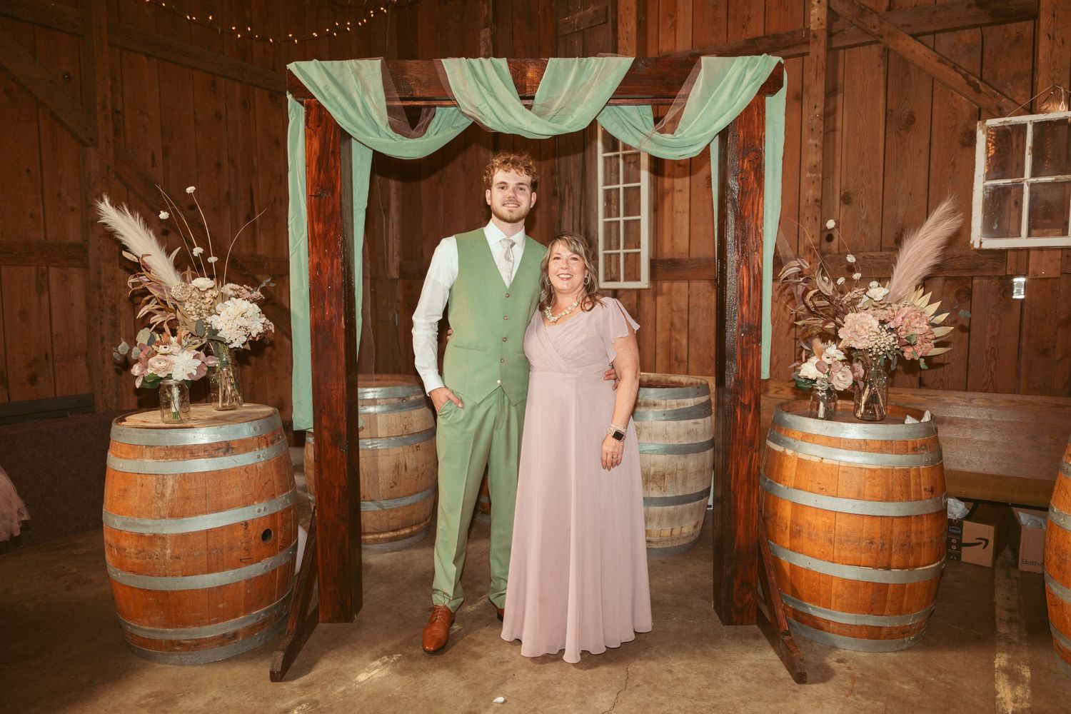 Wedding celebration in a rustic barn venue decorated with wine barrels and string lights.