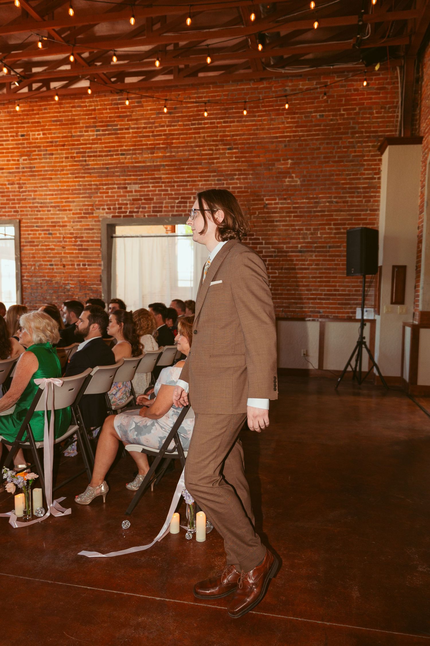 Wedding party members perform choreographed dance moves in a historic brick venue.