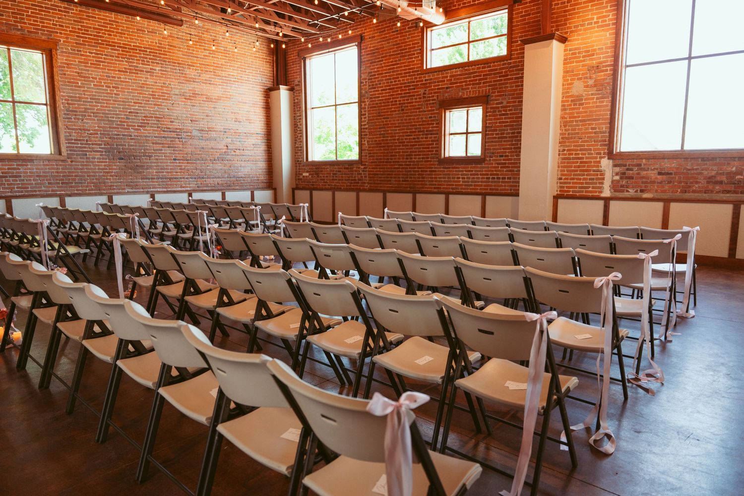 Rows of folding chairs arranged in a rustic brick ceremony space with natural lighting.