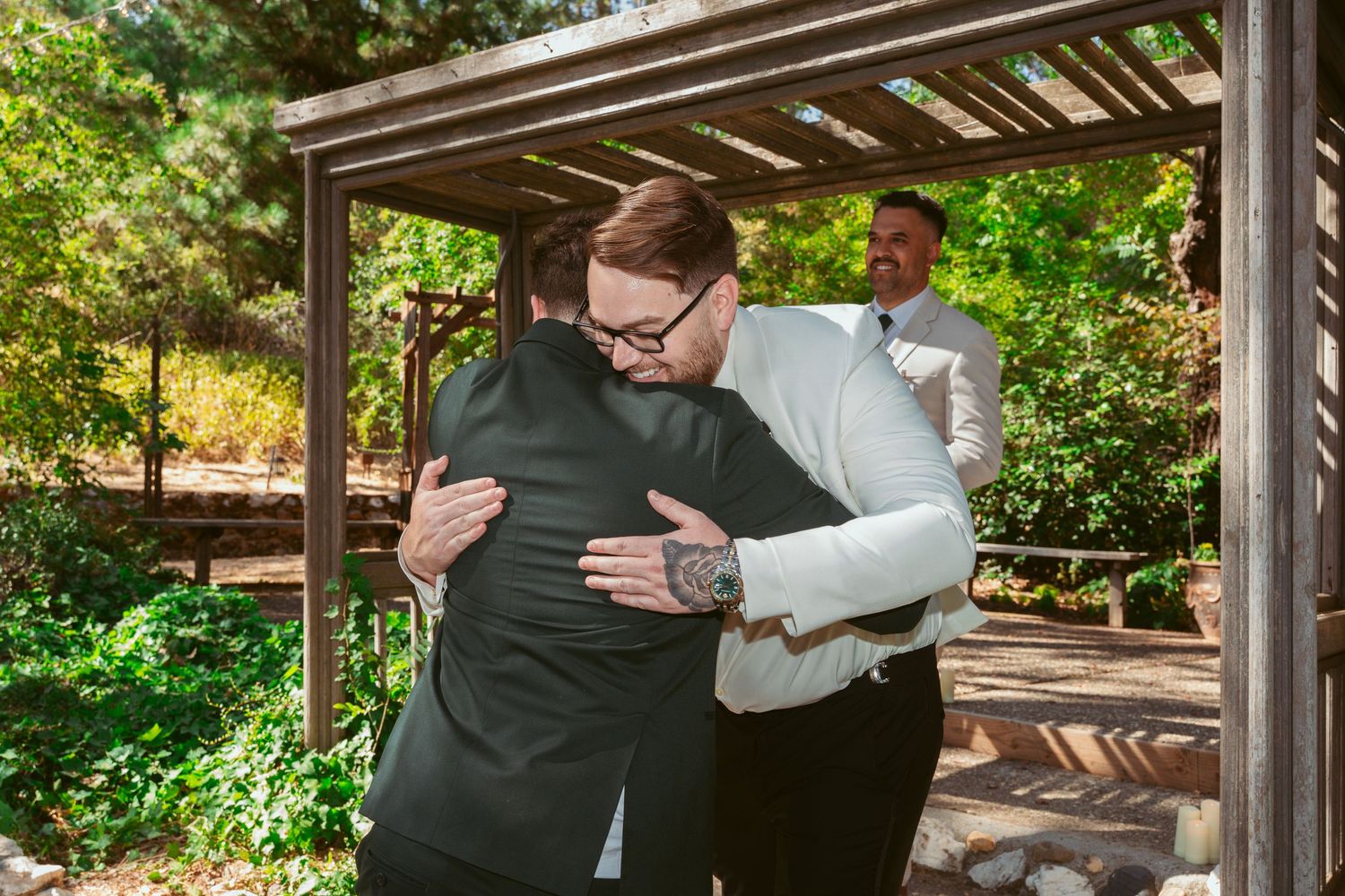 A heartfelt embrace shared during a wedding celebration under a wooden gazebo.