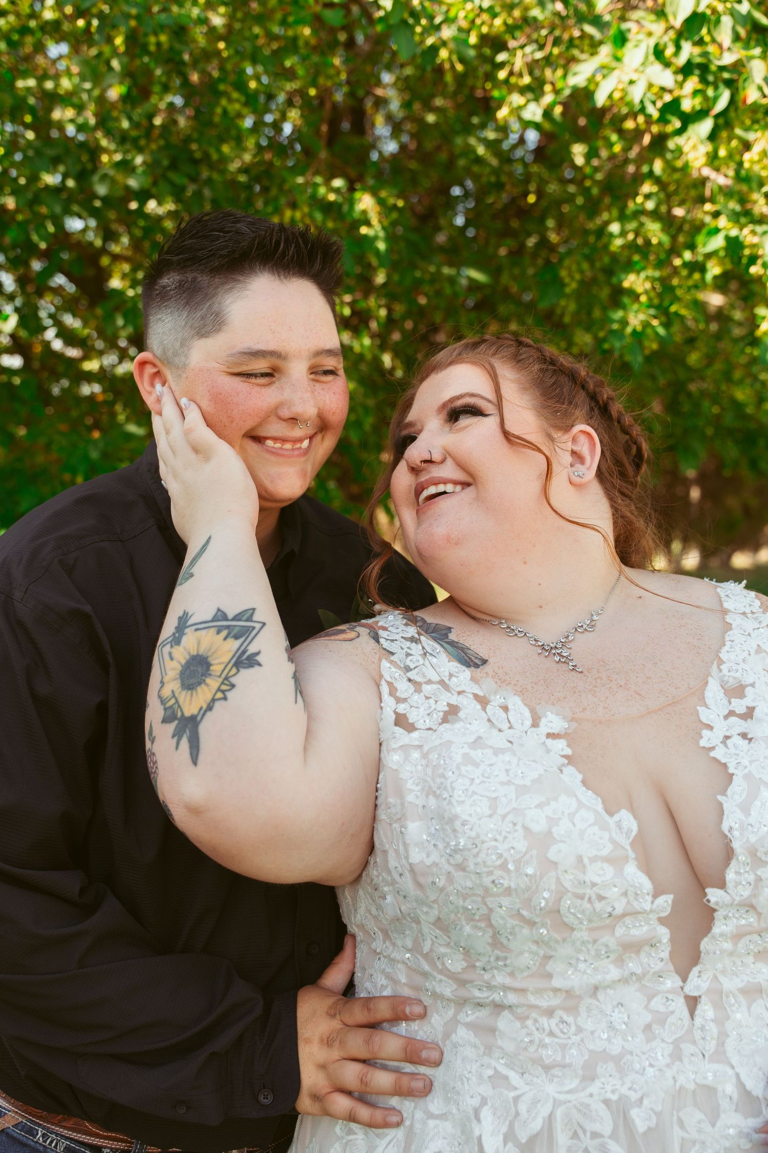 A couple in wedding attire share an intimate moment while smiling and touching faces.
