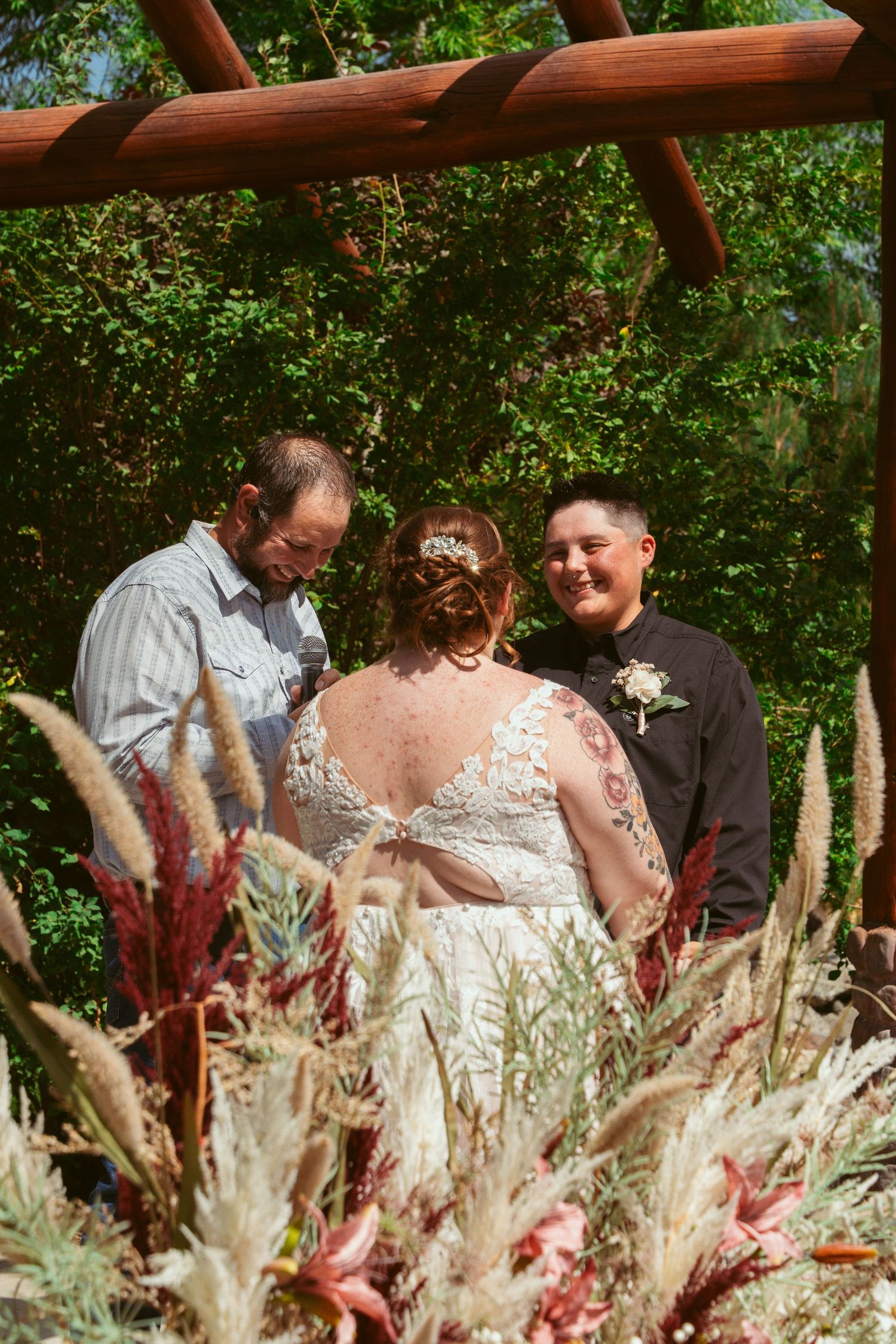 Wedding ceremony taking place outdoors with dried pampas grass decorations in the foreground.