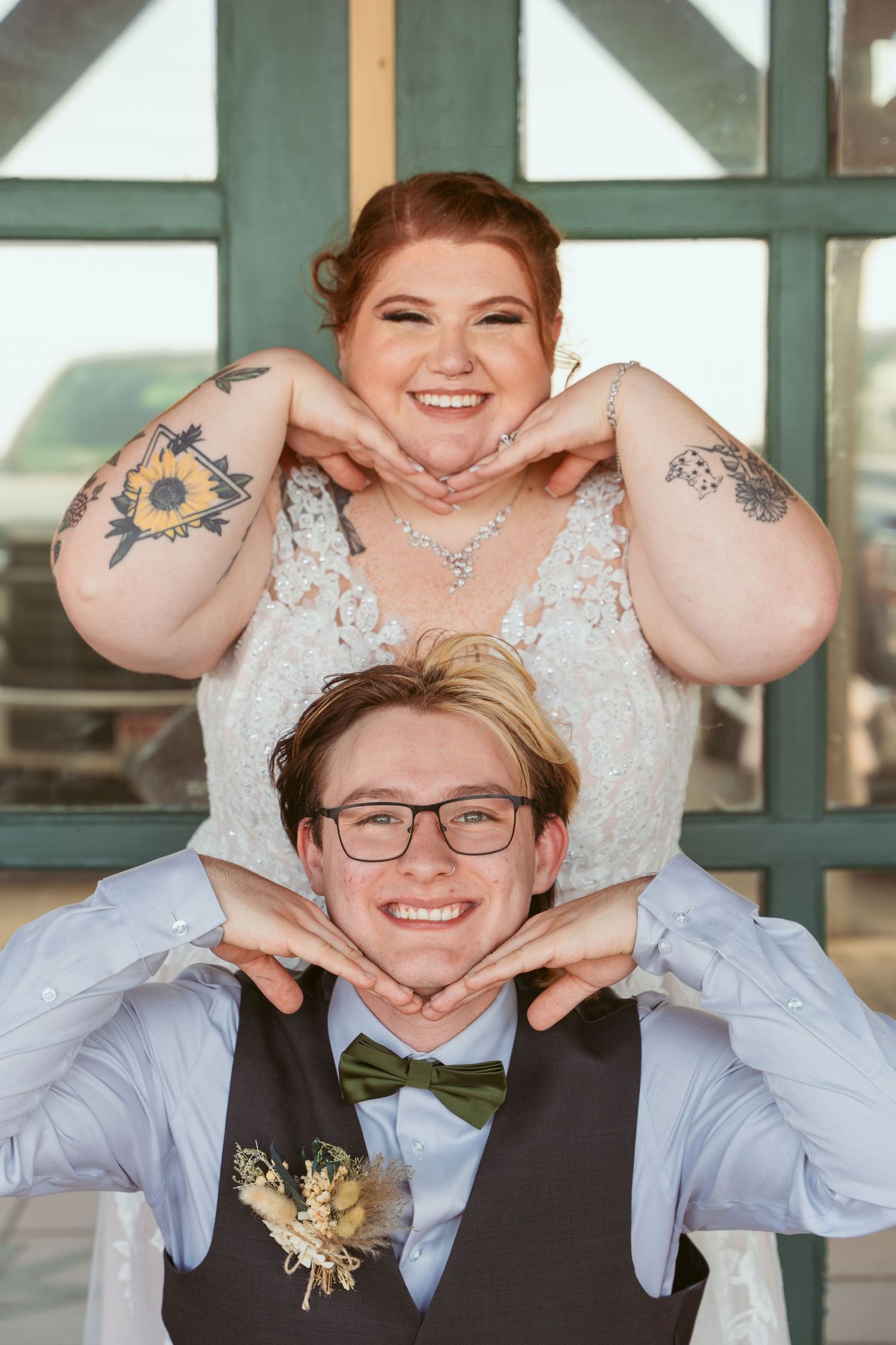 Fun heart-shaped hand gestures create joyful wedding photo moments against teal doors.