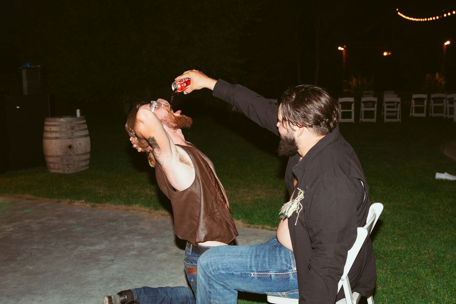 Two people dancing energetically at a nighttime outdoor gathering.