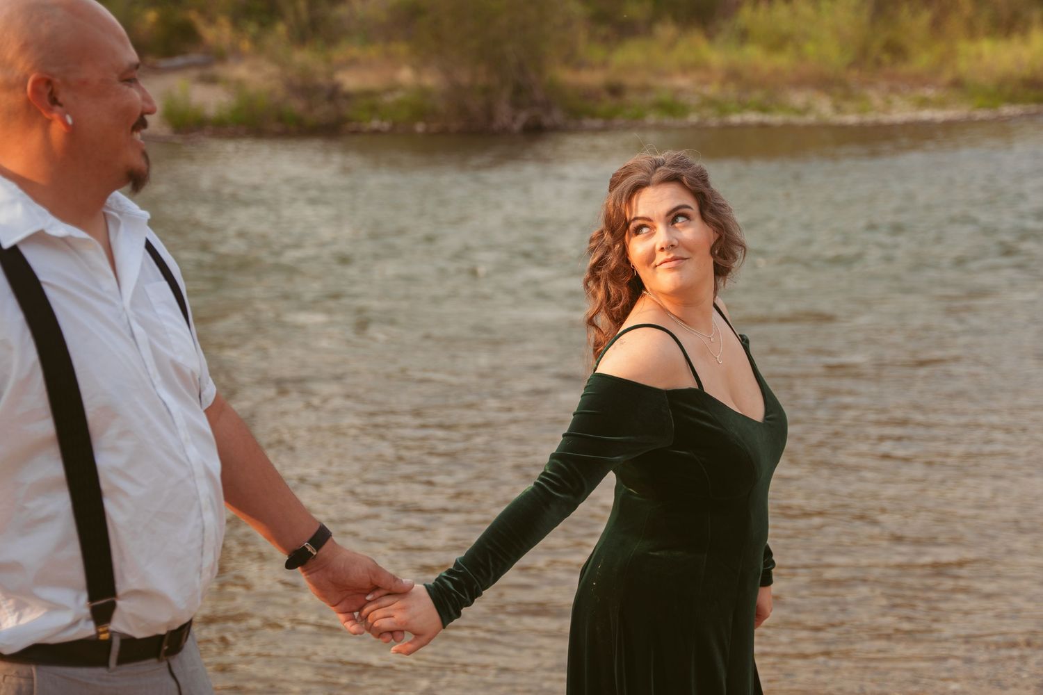 Two people in contrasting black and white outfits share a romantic moment by a lake.