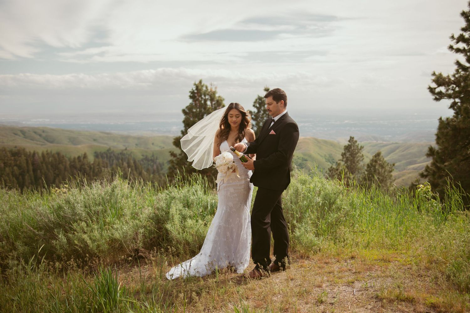 Bride and groom share drinks during their mountaintop wedding celebration at sunset.